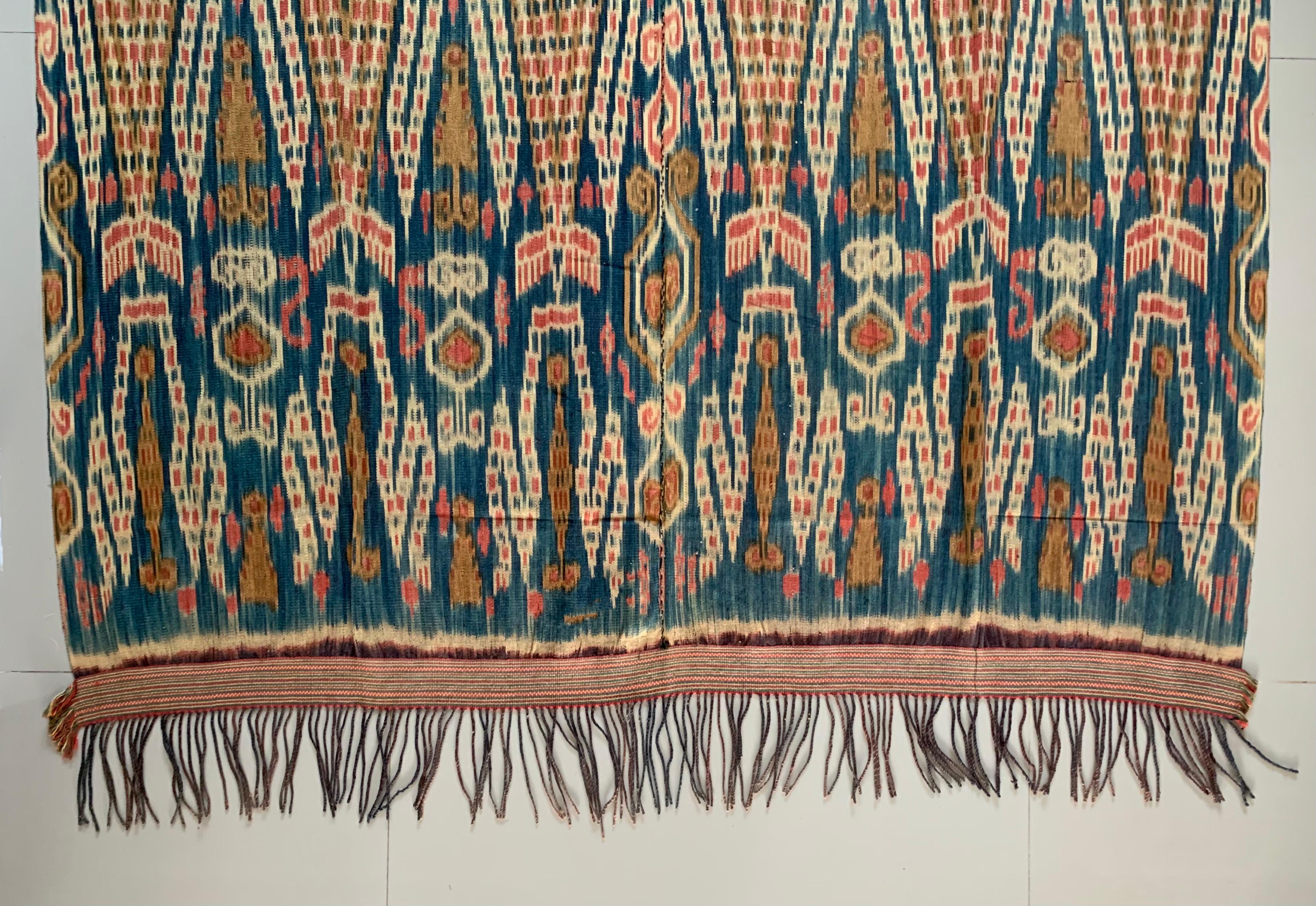 This Ikat textile originates from the Island of Sumba, Indonesia. It is hand-woven using naturally dyed yarns via a method passed on through generations. It features a stunning array of distinct tribal patterns in a predominantly orange hue.