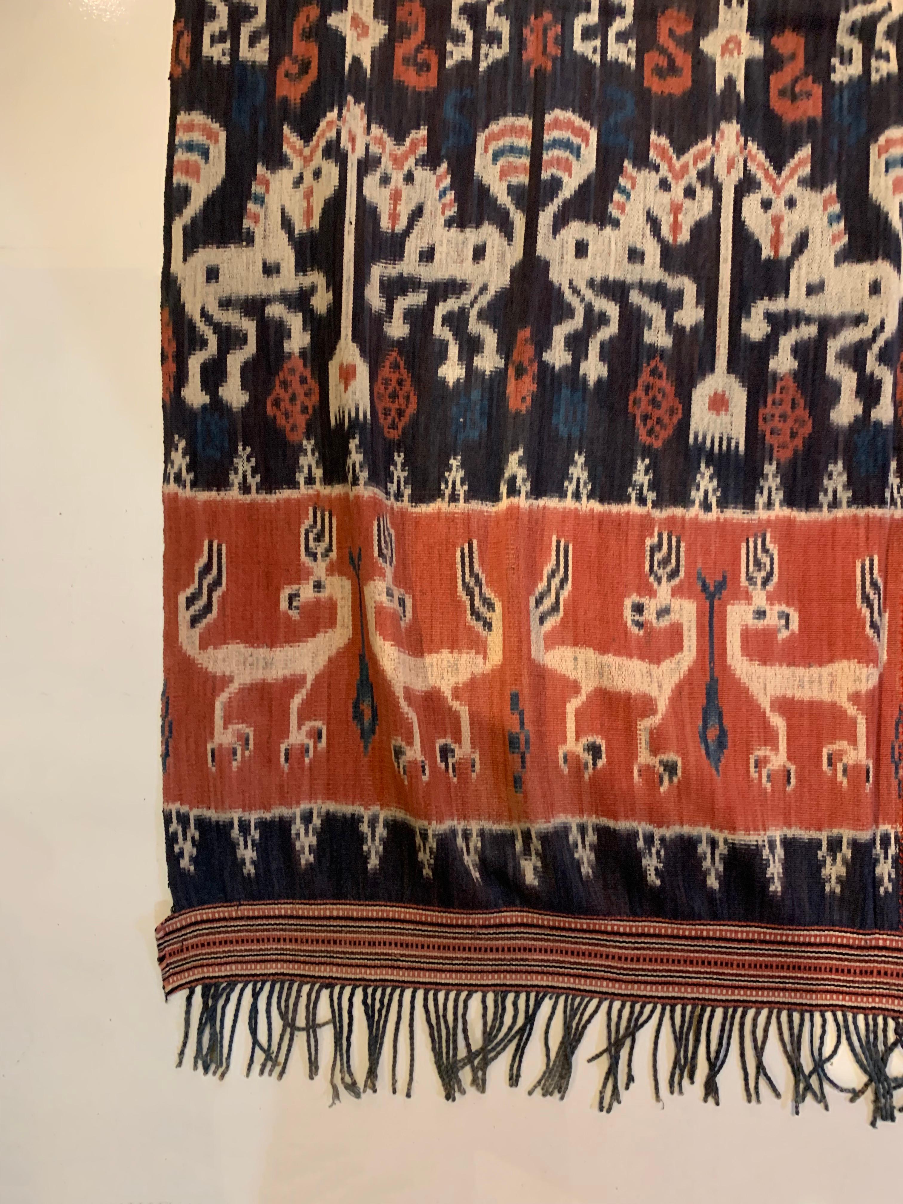 This Ikat textile originates from the Island of Sumba, Indonesia. It is hand-woven using naturally dyed yarns via a method passed on through generations. It features a stunning array of distinct tribal patterns and motifs. Motifs include chickens &