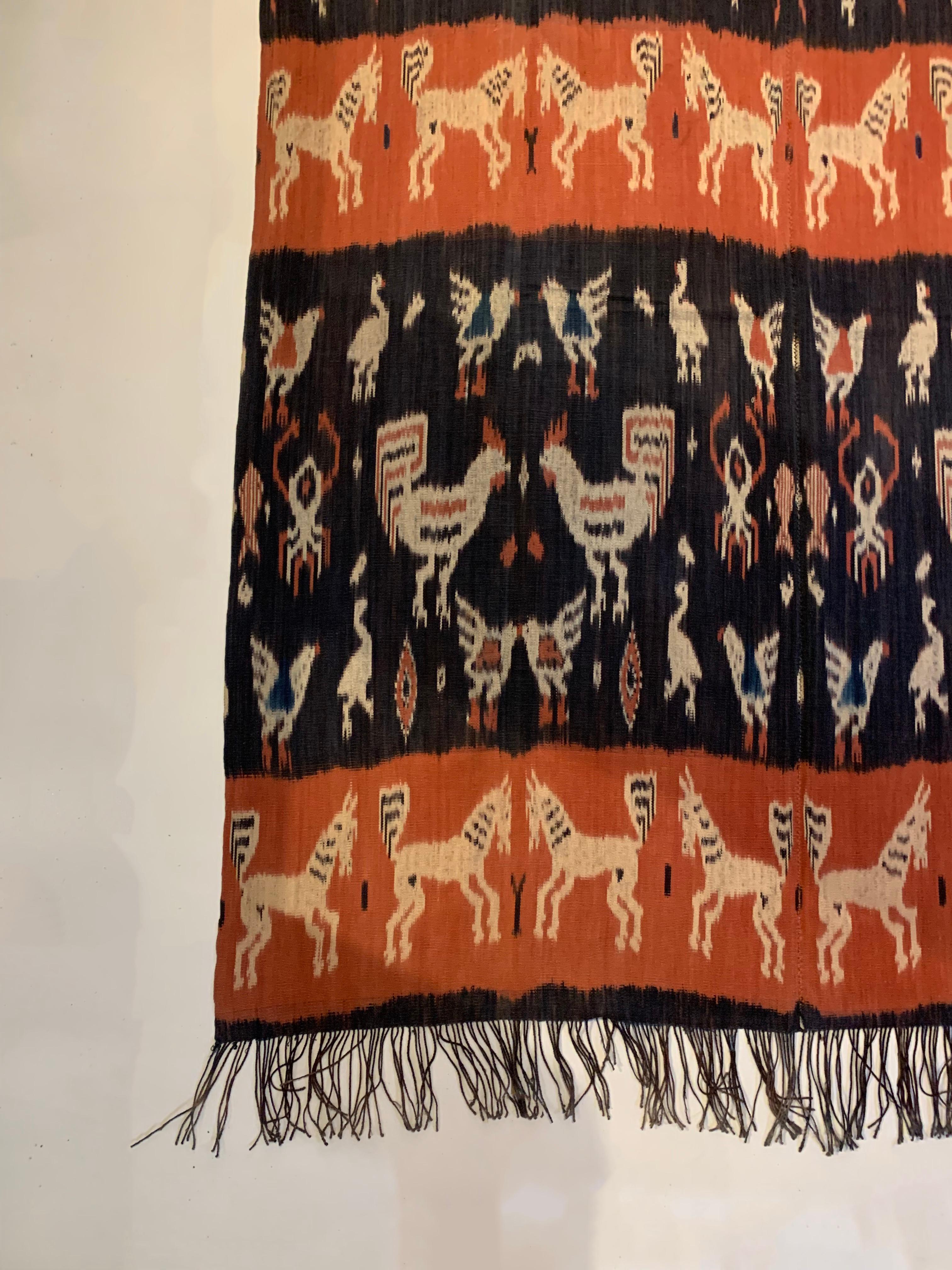 This Ikat textile originates from the Island of Sumba, Indonesia. It is hand-woven using naturally dyed yarns via a method passed on through generations. It features a stunning array of distinct tribal patterns and motifs. Motifs include chickens &