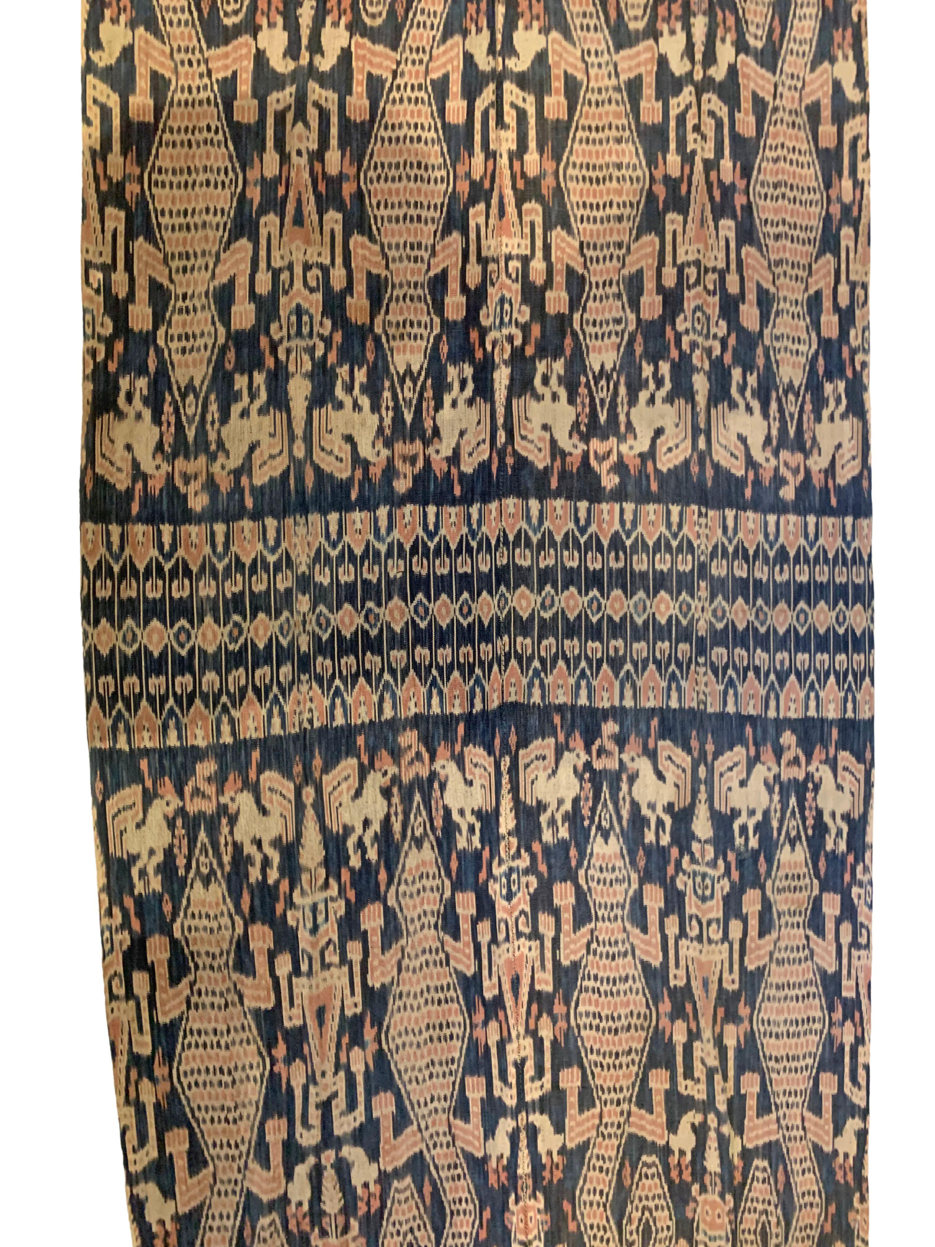 Dieses Ikat-Textil stammt von der Insel Sumba in Indonesien. Es wird mit natürlich gefärbten Garnen nach einer seit Generationen überlieferten Methode handgewebt. Es zeigt eine atemberaubende Vielfalt von Stammesmustern und -motiven. Einzigartig an