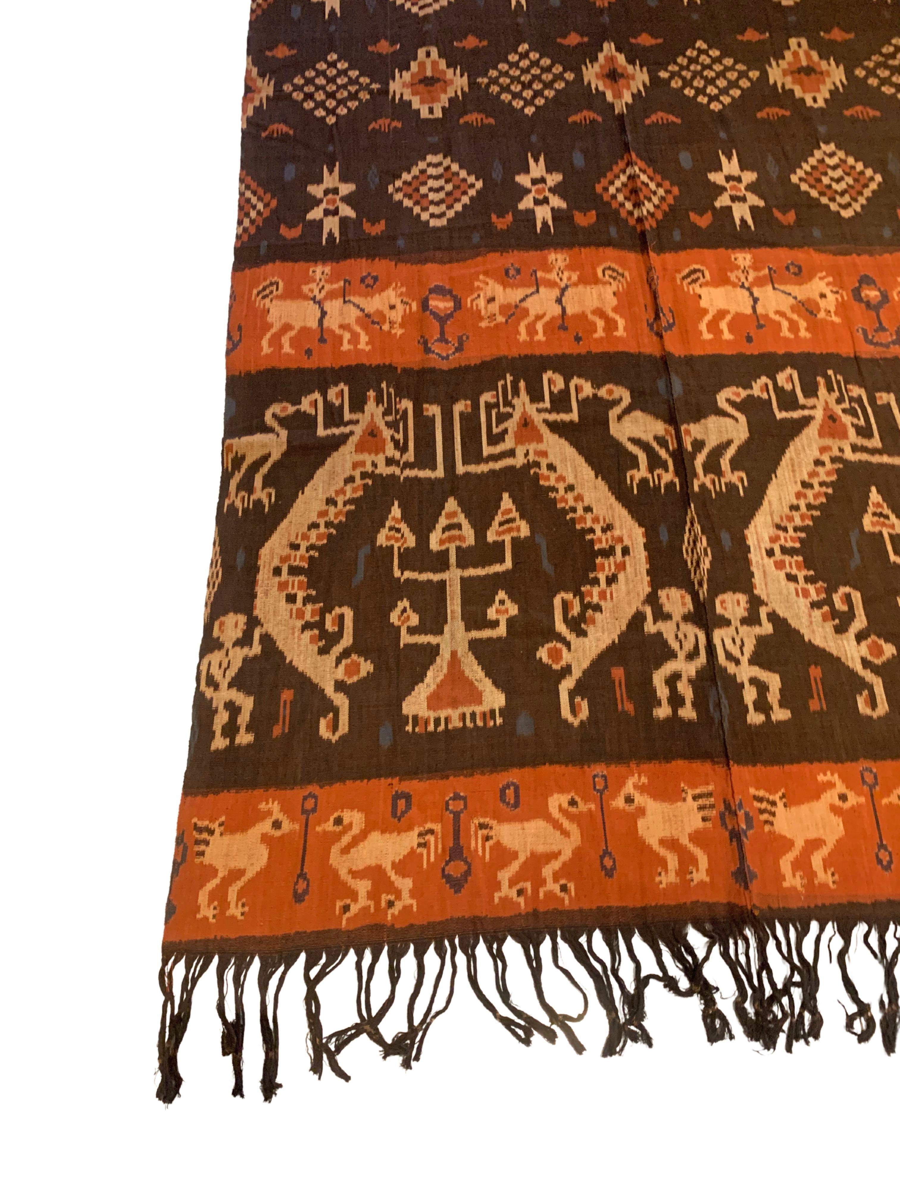 Dieses Ikat-Textil stammt von der Insel Sumba in Indonesien. Es wird mit natürlich gefärbten Garnen nach einer seit Generationen überlieferten Methode handgewebt. Es zeigt eine atemberaubende Vielfalt von Stammesmustern und -motiven. Es sind die