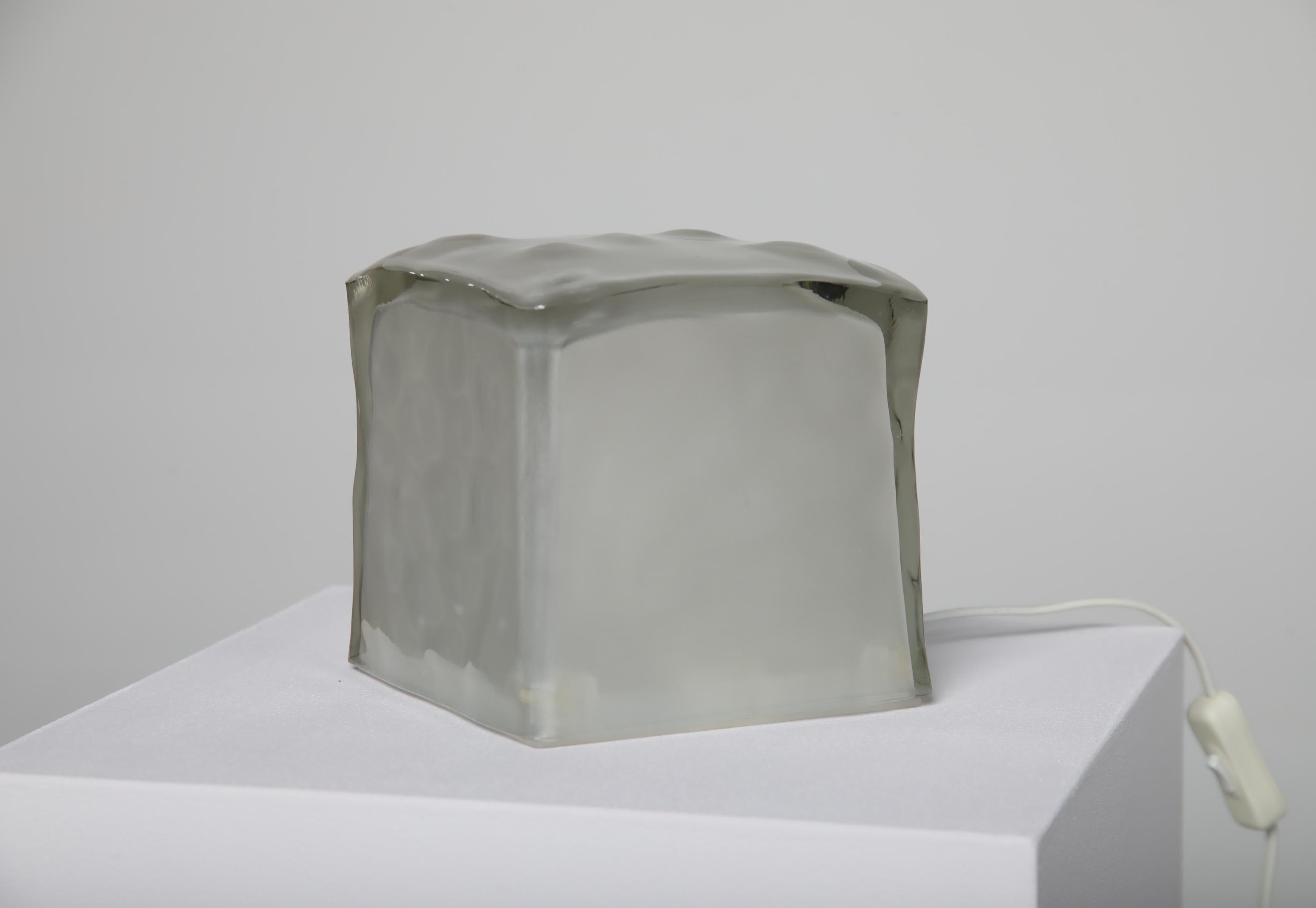 The “Iviken” table lamp, often referred to as the “Ice Cube” lamp, was produced by IKEA during the 1990s and is recognized for its compact glass construction and minimal Scandinavian expression. The lamp is made from thick, frosted glass that gives
