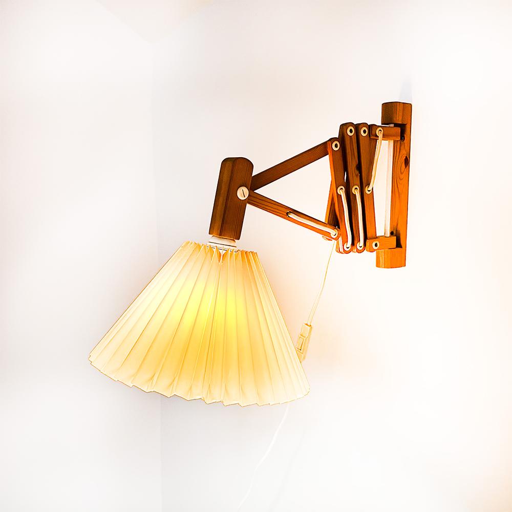 Ikea V9004 scissor wall light, 1989.

Solid pine wood and folded plastic lampshade.

E27 bulb socket.

The wiring can be changed position as well as the screen.

The classic screen is the original and has some cracks, visible in the