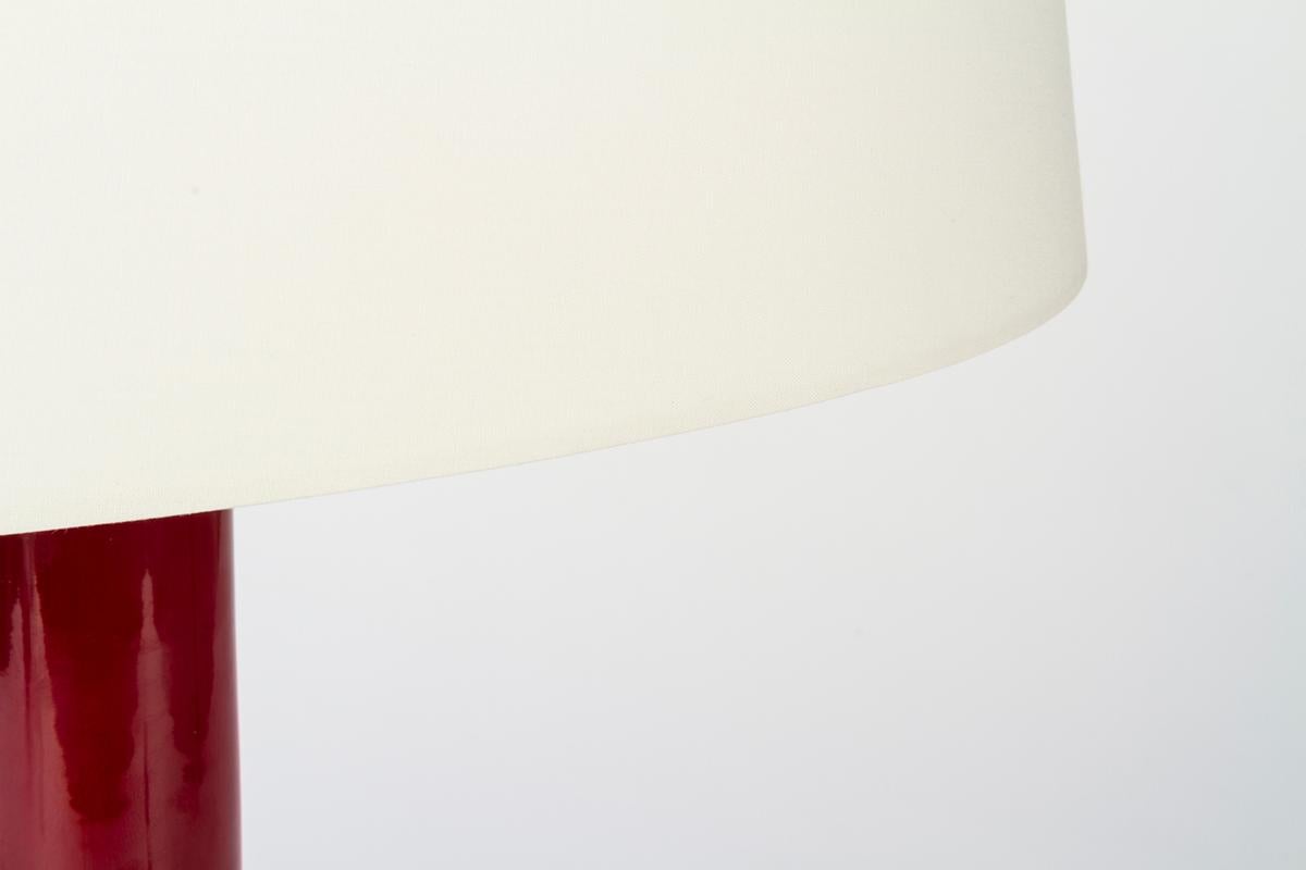 Ikonica, table lamp with body and base made of dark red, glazed ceramic from the famous ceramic district of Bassano del Grappa; lampshade made of cream-white fabric.
The warm glaze of the ceramic and the oval lampshade make this lamp designed by