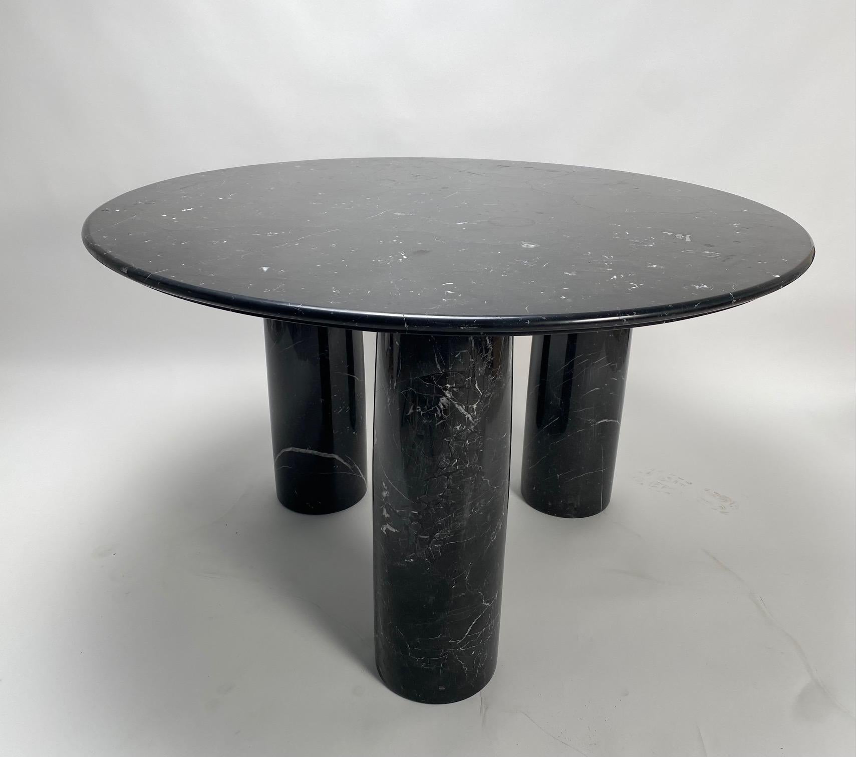 La table, conçue par le célèbre architecte italien Mario Bellini pour la société Cassina, a été imaginée dans les années 1970 et s'inspire de l'architecture des antiquités romaines. Ce spécimen a un sommet rond en marbre noir épais et trois grands