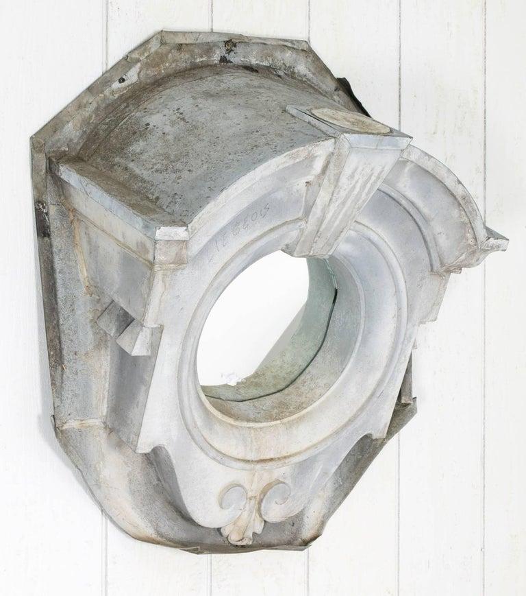 Beautiful Oeil de Boeuf or “ox-eye” zinc window frame from the 19th century, converted into a statement mirror. This ox-Eye architectural zinc dormer window features a slightly tilted inset mirror where there was once a windowpane. This Baroque