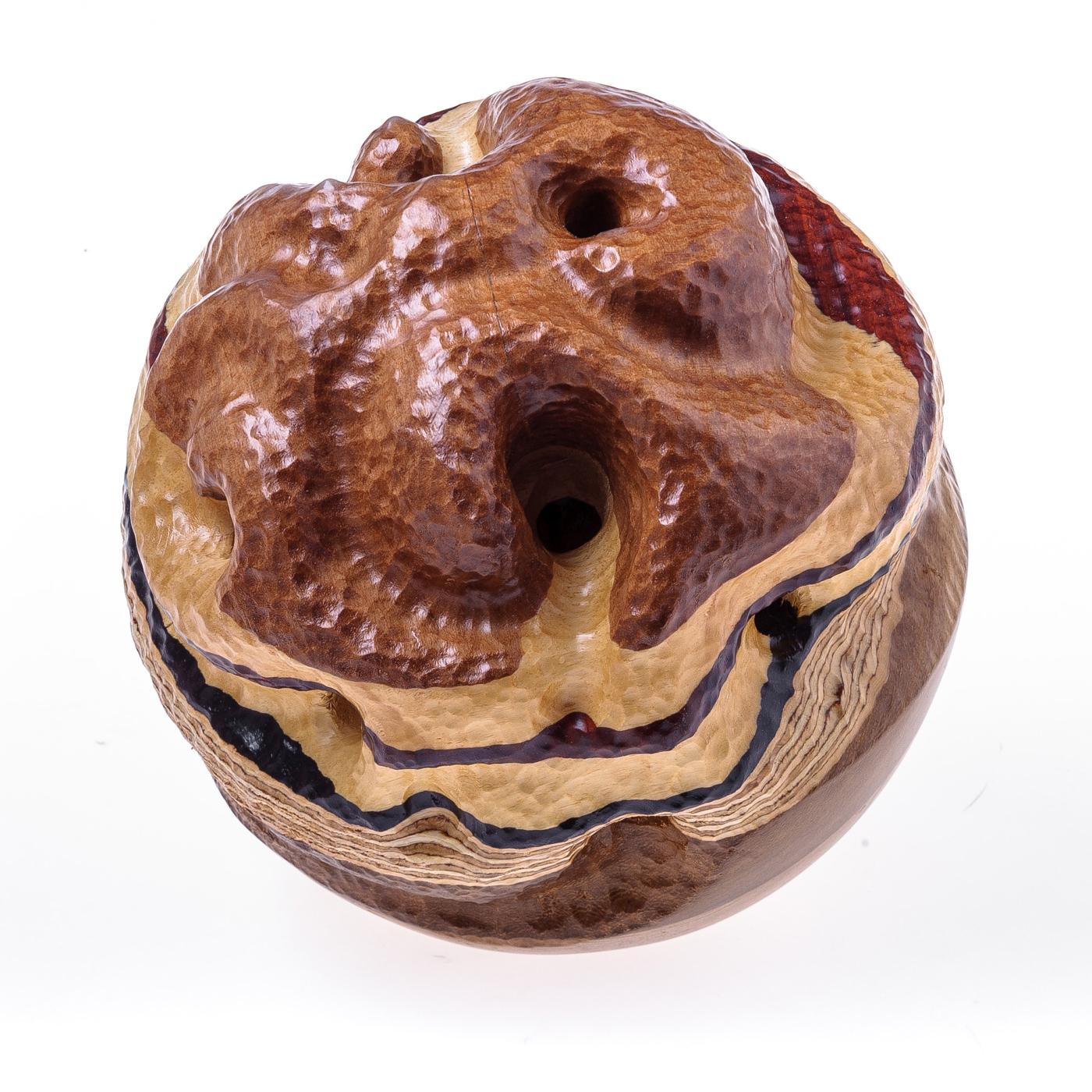 Craftsmanship takes center stage in this remarkable wooden sculpture inspired by the subtle elegance of trees and nature. The sculpture is fashioned of layers of light and dark wood, hand-assembled and carved to form a captivating sphere that boasts