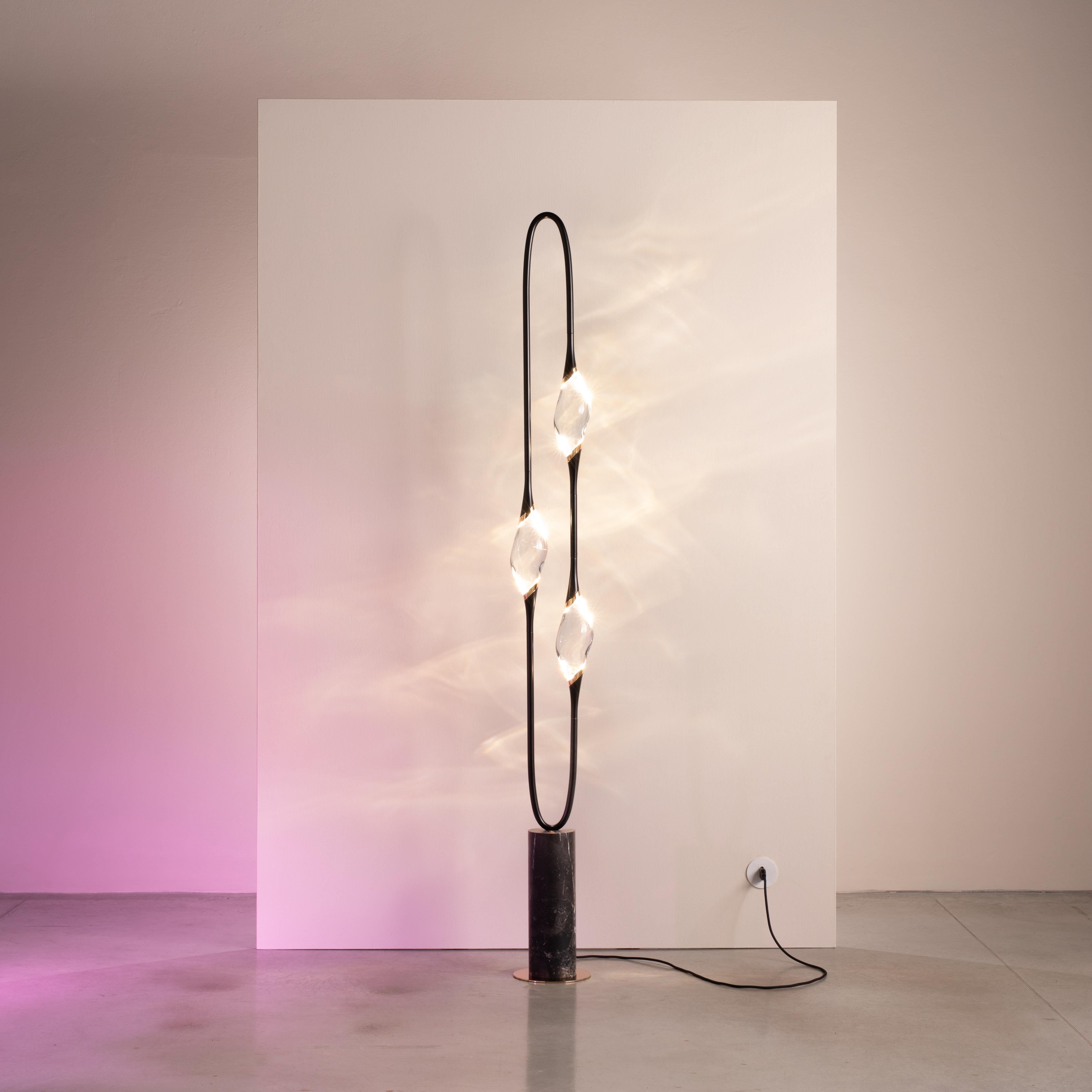 La lámpara de pie Il Pezzo 12 tiene una impresionante forma circular que lleva las tres fuentes de luz en su rotación sin fin, apoyada en una base de mármol que realza
su limpieza y pureza. Iluminados por LED, los tres cristales macizos crean un