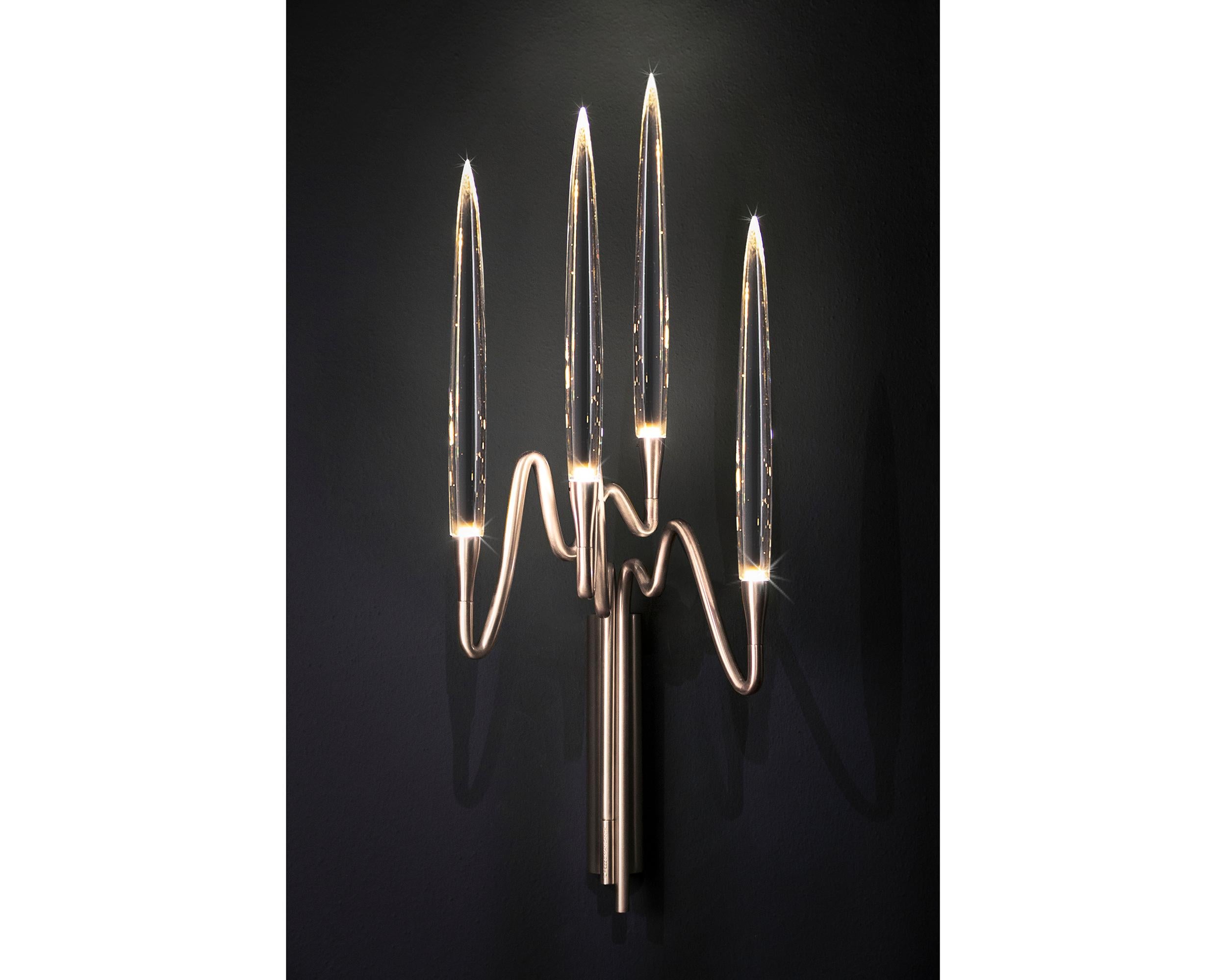 Inspired by Arabic calligraphic art and the icon of the classical candelabrum is Il Pezzo 3, a collection of lamps with a hand-forged brass structure and elegant “candles” crafted from hand blown crystal, according to the noble Tuscan artisan