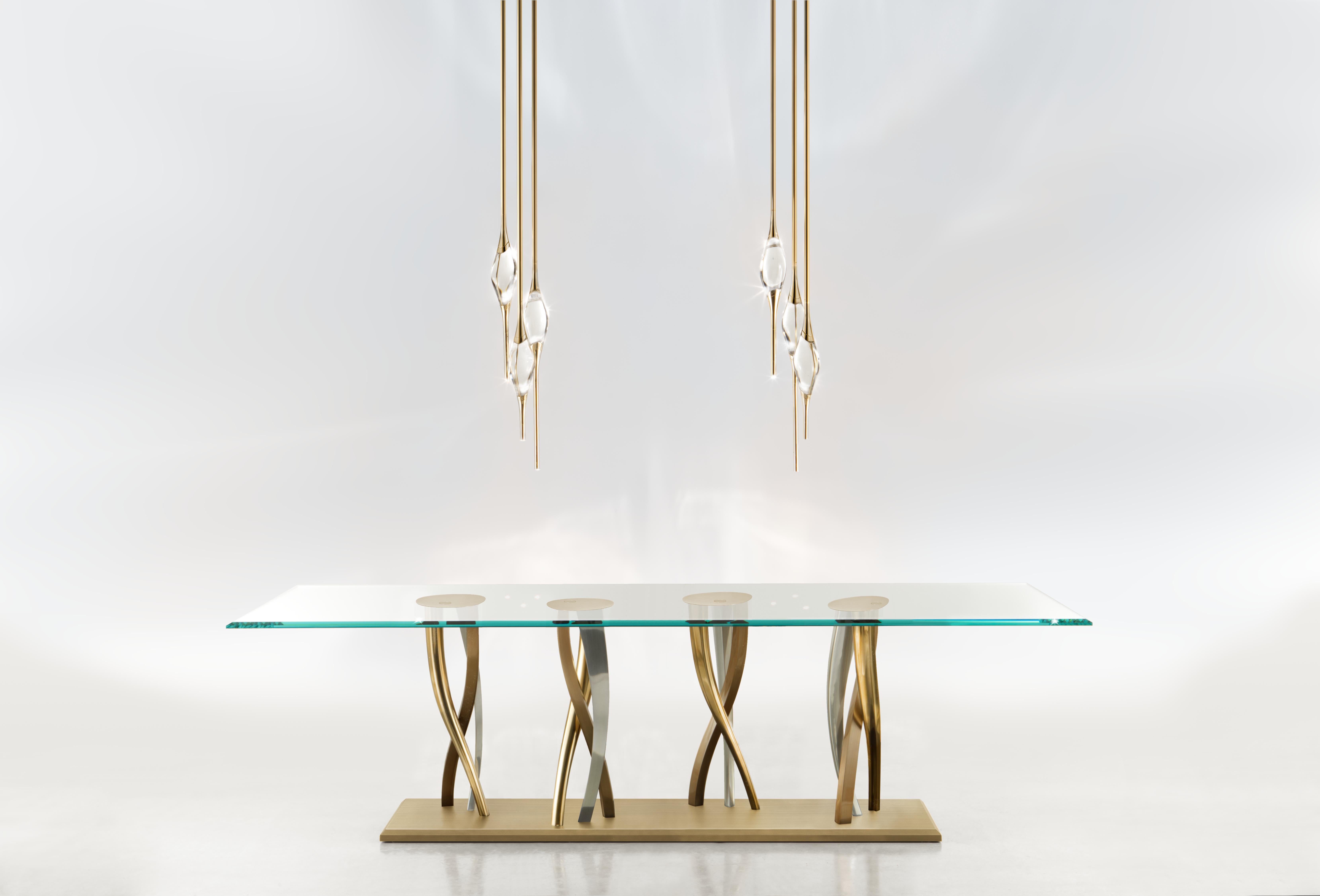 Une forêt étincelante de pieds torsadés fabriqués par moulage, dans des finitions nickel, champagne et bronze, crée une étonnante exposition de couleurs contrastées. Cette base impressionnante offre un soutien inébranlable au plateau de table en