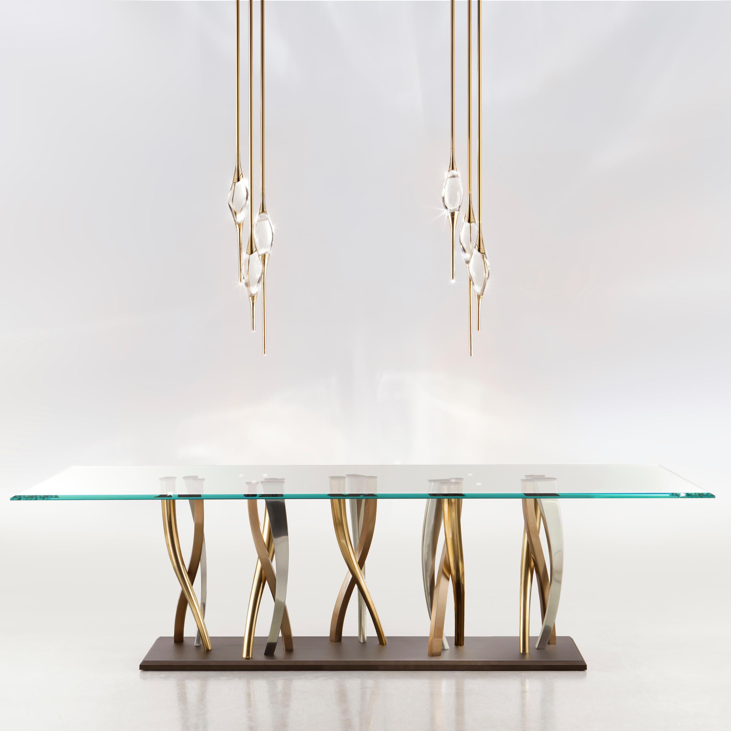 A sparkling forest of twisted legs made by casting, in nickel, champagne and bronze finishes, creates a stunning display of contrasting colors. This awe-inspiring base provide unwavering support to the extra clear glass tabletop, allowing its