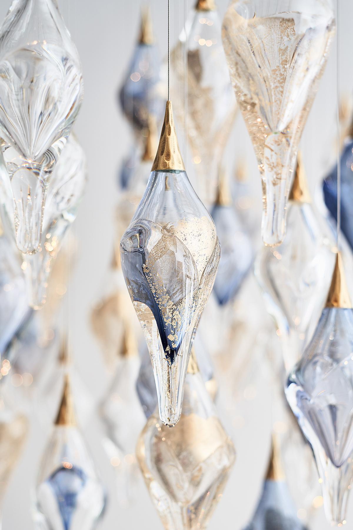 This shimmering jewel of a chandelier is made using layered blown glass that is stretched into elongated diamonds. The offset arrangement creates a sparking, striking form in space.

90 glass diamonds perfectly captures the light from the above
