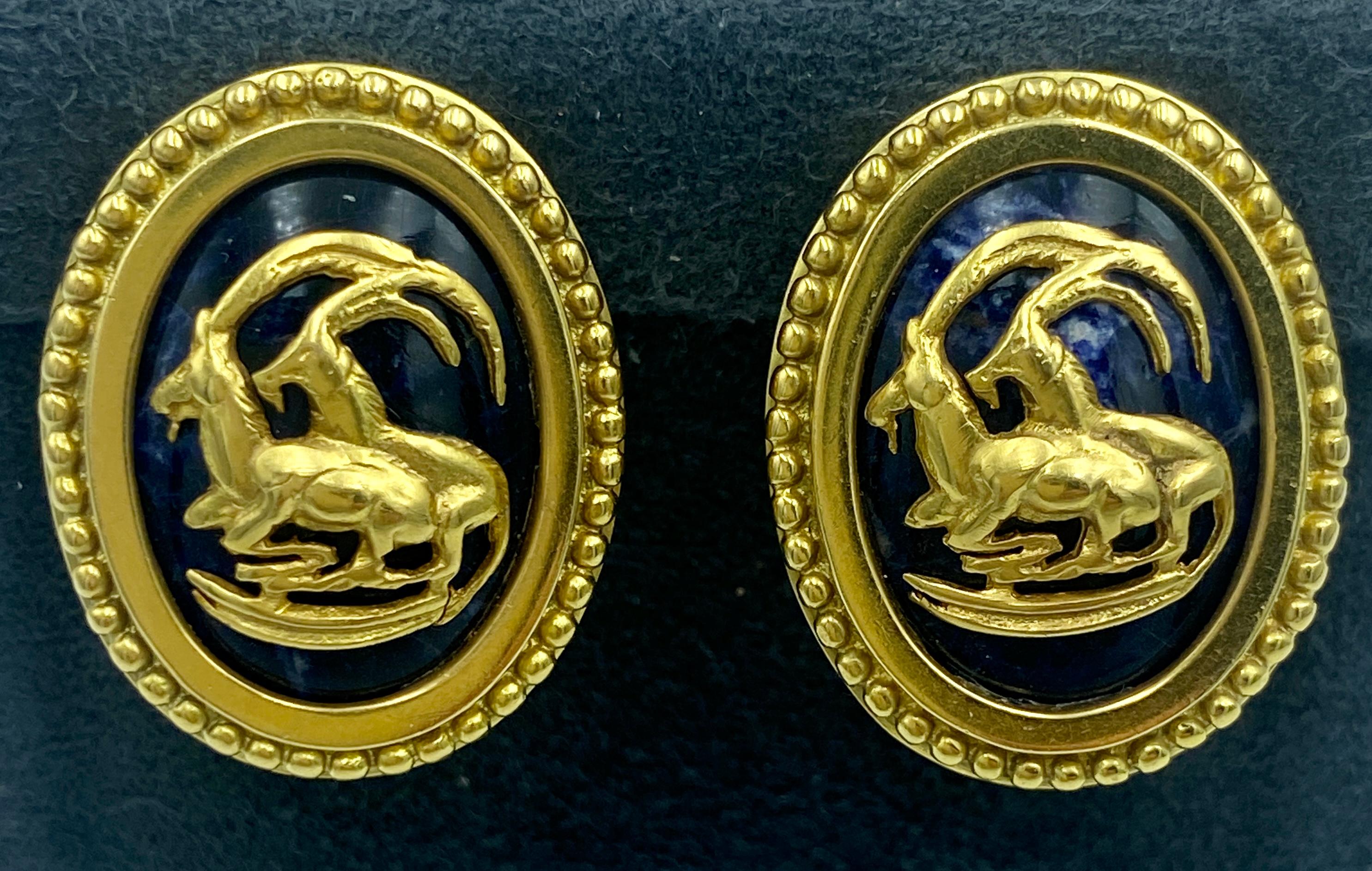 Ces boucles d'oreilles à pince de Lalaounis des années 1970 ont la forme de médaillons ornés de motifs de chèvres de montagne. Réalisé en or 18 carats, le design est centré sur un cabochon de lapis-lazuli.

Ils font partie d'un ensemble avec un