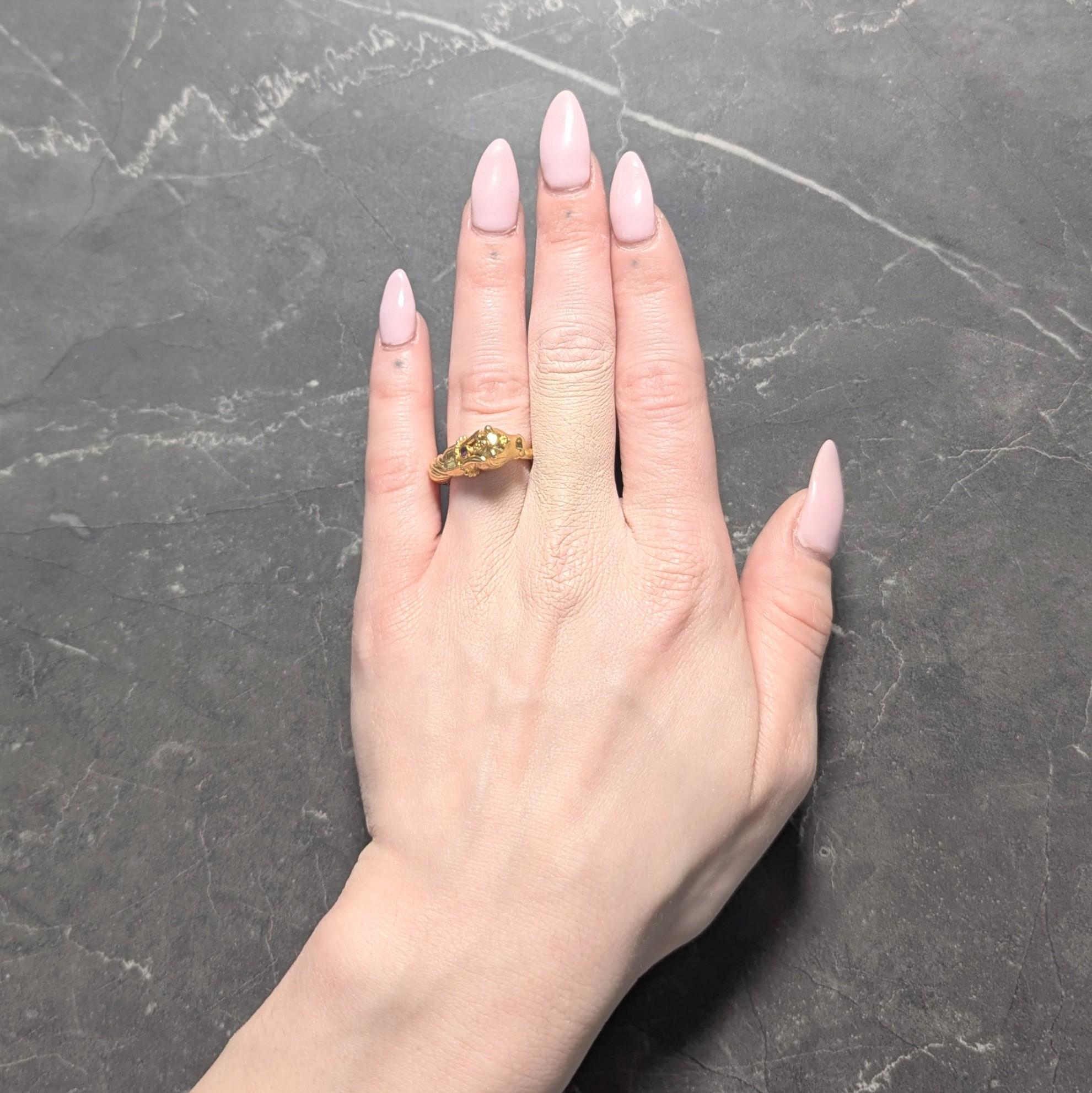 Designed as a bypass style ring terminating with a highly rendered goats head
With grooved featured and granulated detail - accented by bezel set ruby
Measuring 2.0 mm round and transparent purplish red in color
Completed by twisting rope motif