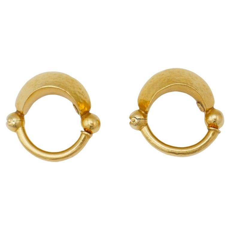 A pair of small hoop earrings by Greek designer Ilias Lalaounis. Made of 22k gold, with Lalaounis' signature hammered texture. Stamped with the maker's mark and a hallmark for 22k gold.
Measurements: diameter is 1 1/8