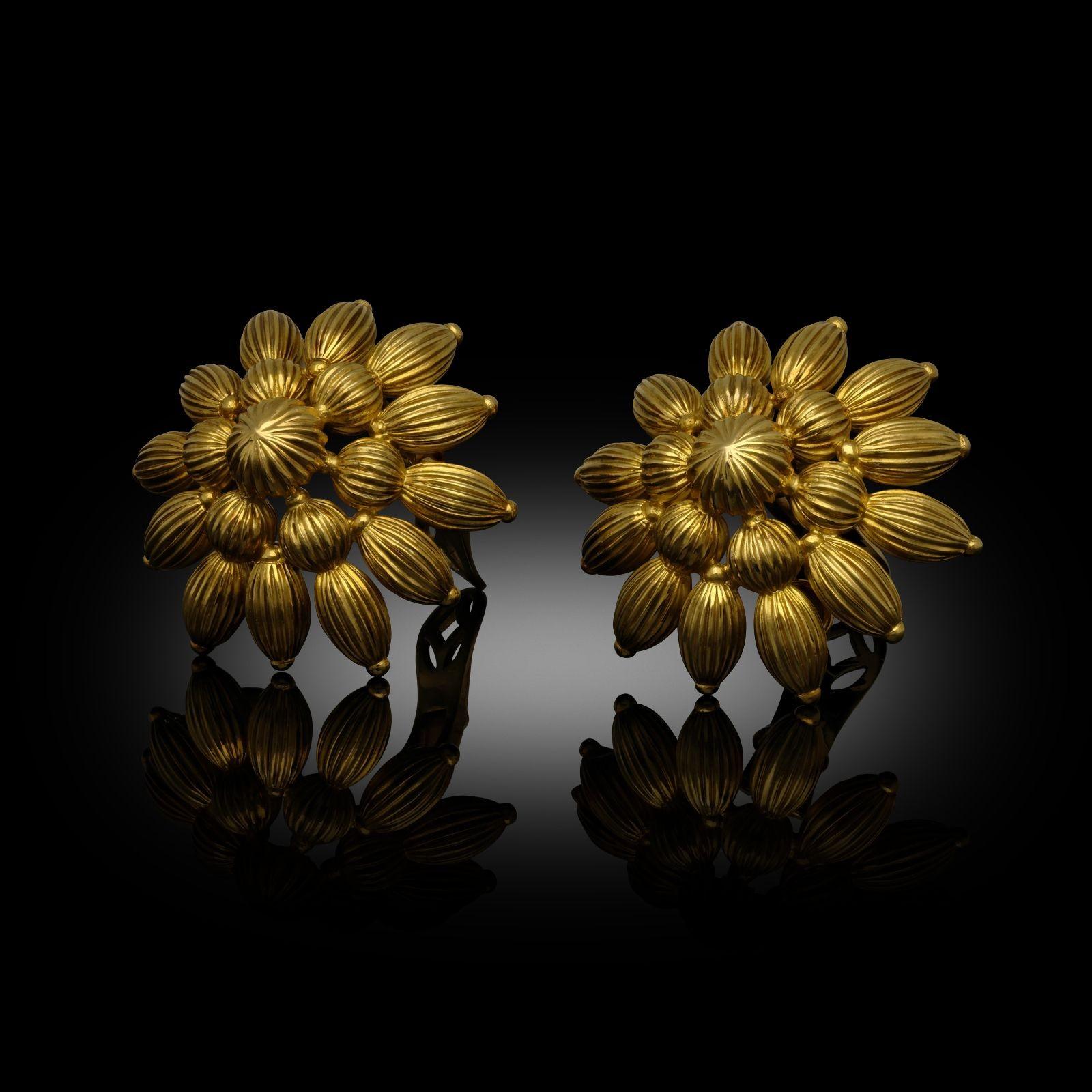 A bold and striking pair of ear clips by Ilias Lalaounis c.1970s from the 'Byzantine' collection, each designed as a large openwork stylised flower head formed of fluted bead shaped motifs in spherical or elongated melon shapes, centred with a