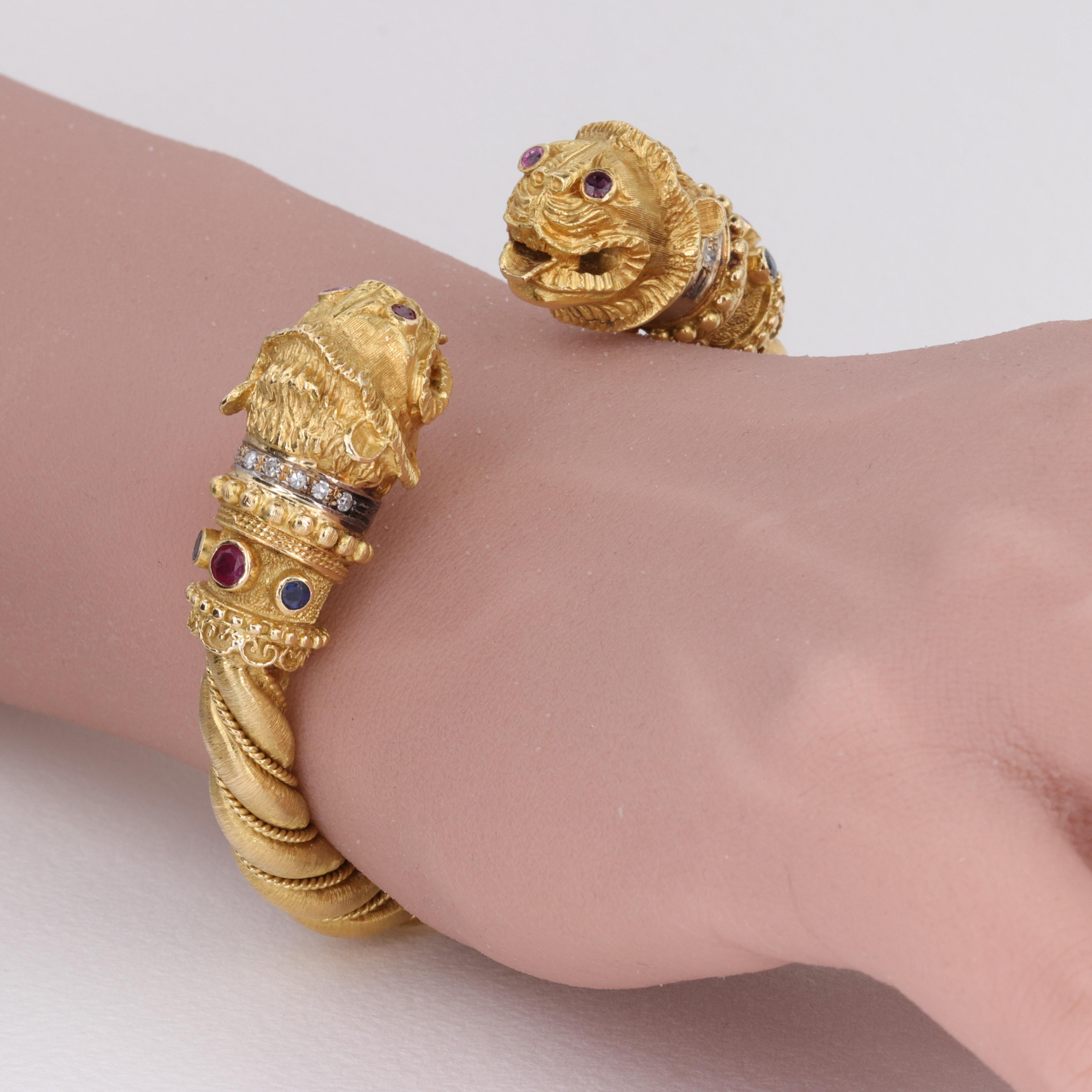 An extremely well made bangle bracelet by iconic Greek jewelry designer Ilias Lalaounis, this bangle depicts 2 Chimera heads atop a textured and twisted 18 karat yellow gold hinged bangle. The chimeras are adorned with vivid red ruby eyes, and