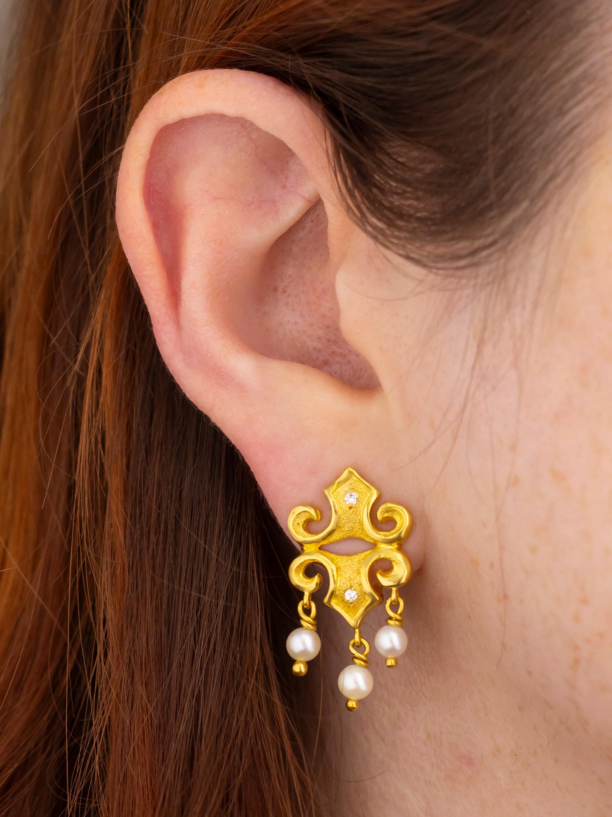 Realizzati dalla più famosa casa di gioielli greca, questo paio di orecchini a goccia in oro, diamanti e perle sono estremamente chic. La coppia, che probabilmente ha solo 20 o 30 anni, è stata realizzata in oro giallo 18 carati con diamanti taglio