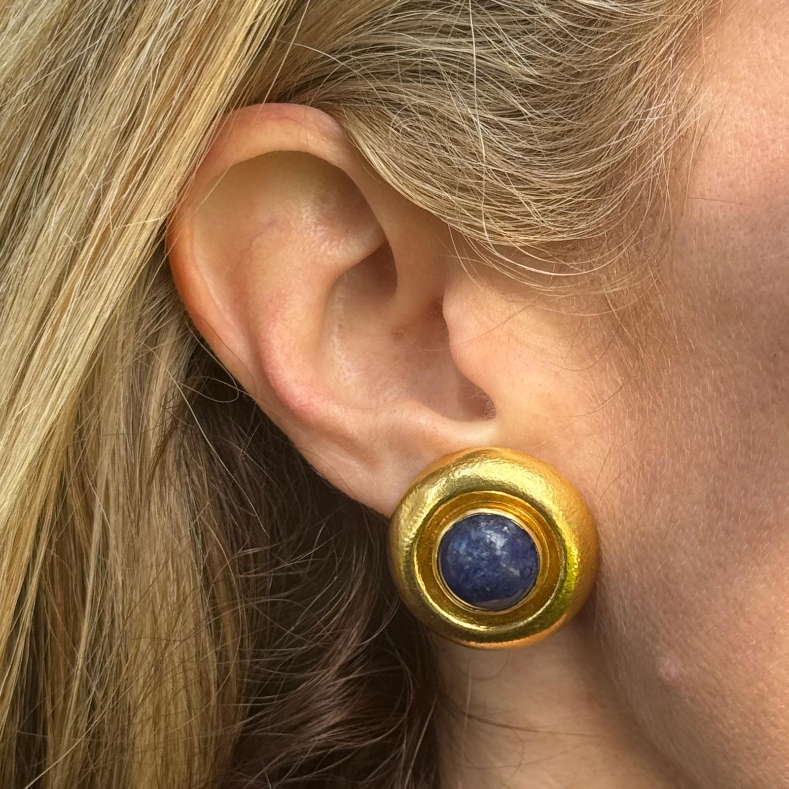 These exquisite Ilias Lalaounis button earrings showcase the designer's signature blend of ancient inspiration and modern craftsmanship. Crafted in 18k yellow hammered gold, the round earrings feature rich sodalite cabochons at their center, adding