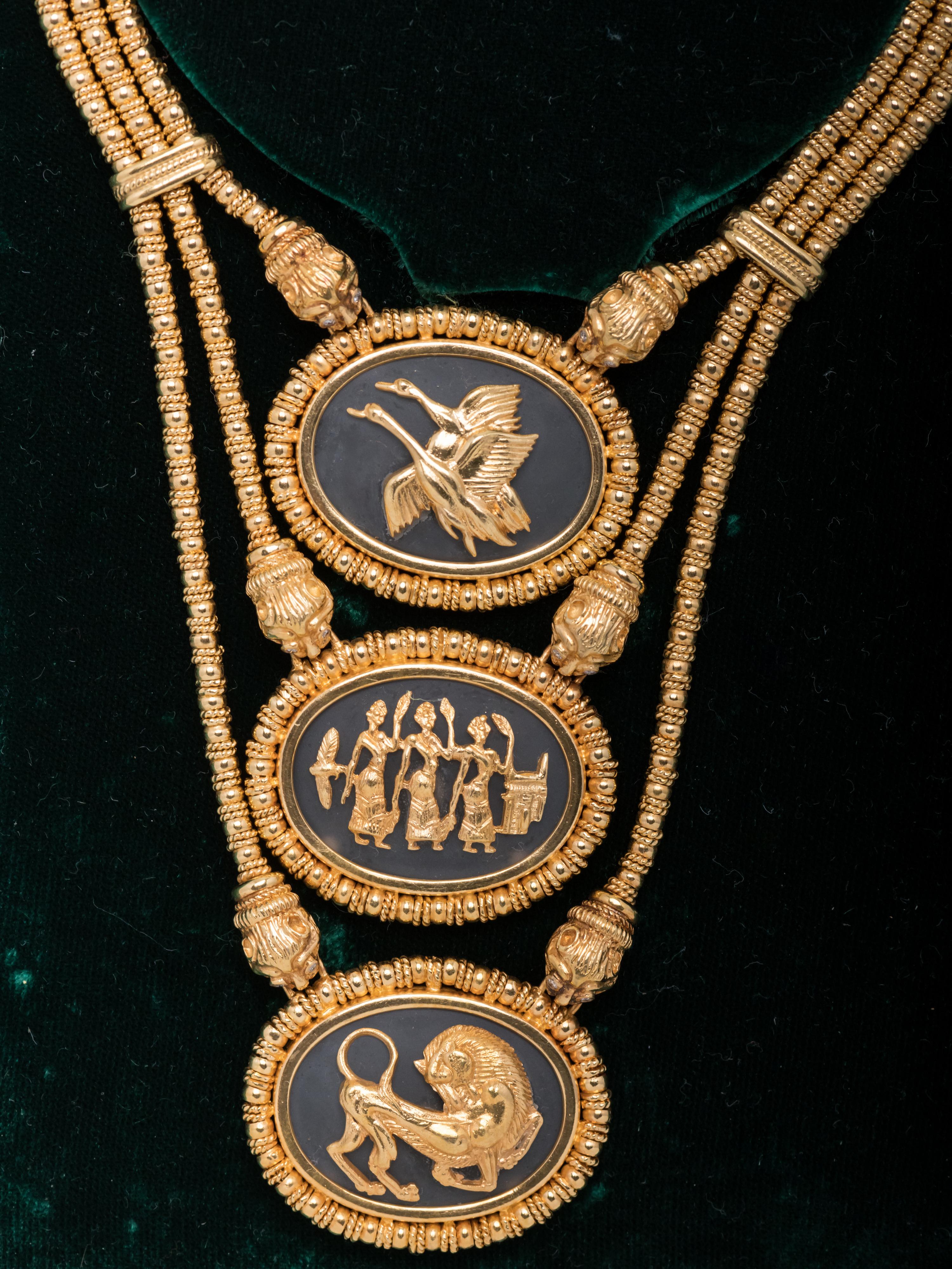 18 karat gold signed Ilias Lalaounis triple stranded necklace with three oval rock crystal medallions; one with 18 karat gold flying geese, the second with three Grecian women and the third with an allegorical lion. The medallions are suspended from
