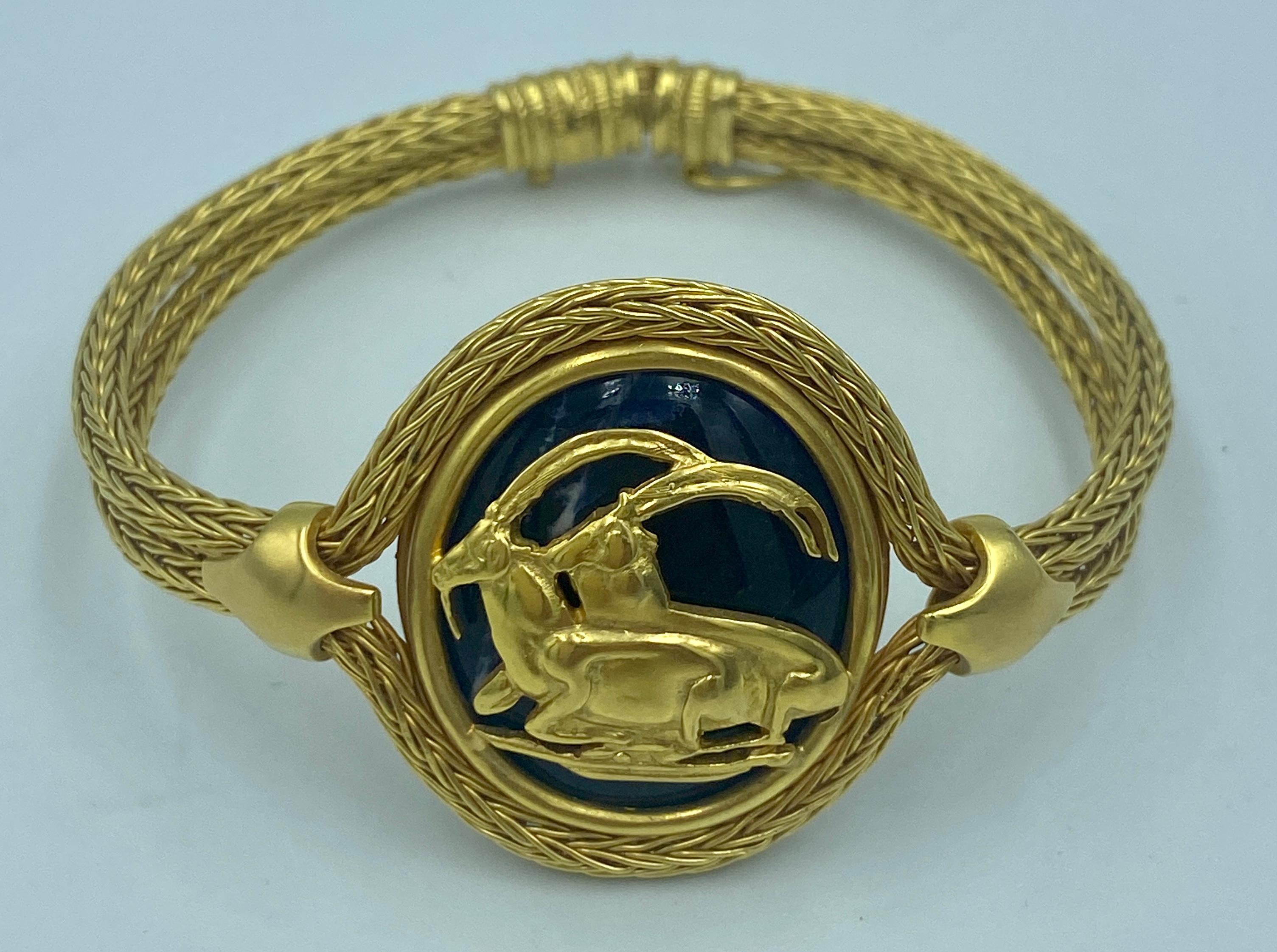 Ce magnifique bracelet Lalaounis des années 1970 a la forme d'un médaillon orné d'un motif de chèvre de montagne. Le médaillon est un lapis-lazuli cabochon entouré d'un fil d'or tissé 18k qui constitue le bracelet.

Ce bracelet, réalisé de manière