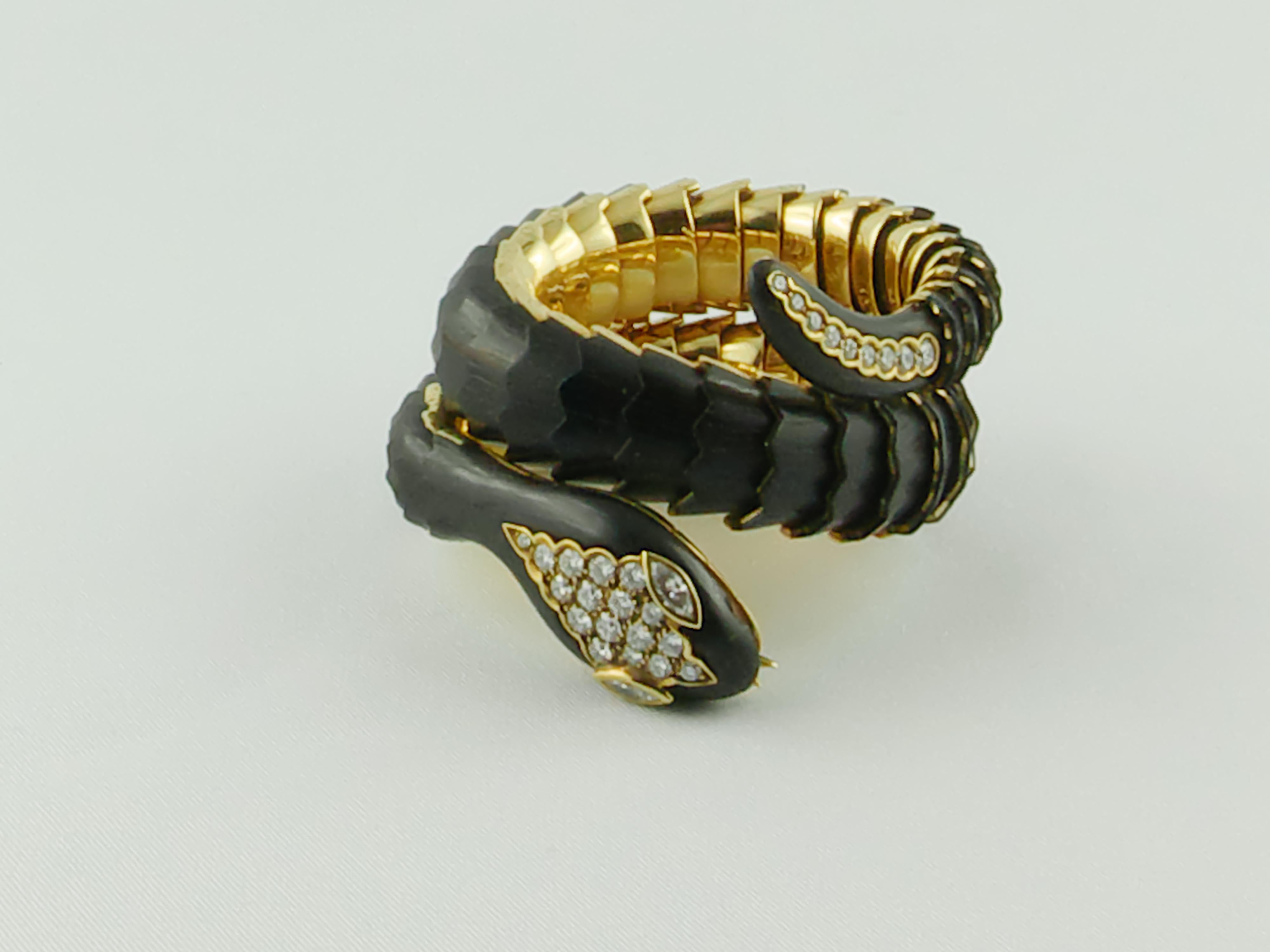 Cet élégant bracelet extensible Illario en or ébène et diamants s'enroule autour du poignet à deux reprises et représente un serpent à écailles artistiquement rendu grâce à des écailles de bois. 
Le bracelet est exceptionnellement réalisé en or
