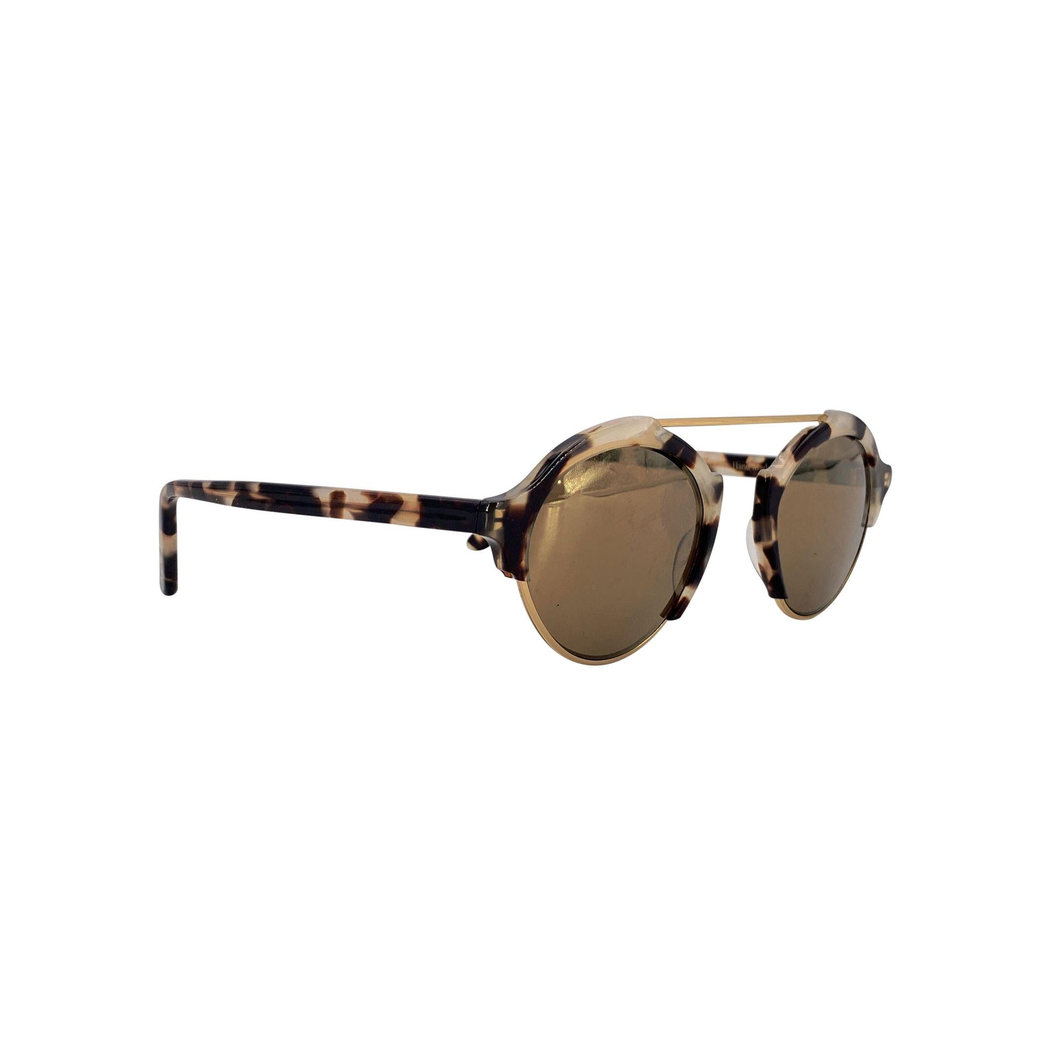 Entra nella giocosa raffinatezza del design italiano degli anni '80 con questi occhiali da sole Illesteva Round Unisex Milan 4 C08. Le lenti rotonde sono incorniciate da un sorprendente mix di acetato trasparente bianco e marrone, mentre una sottile