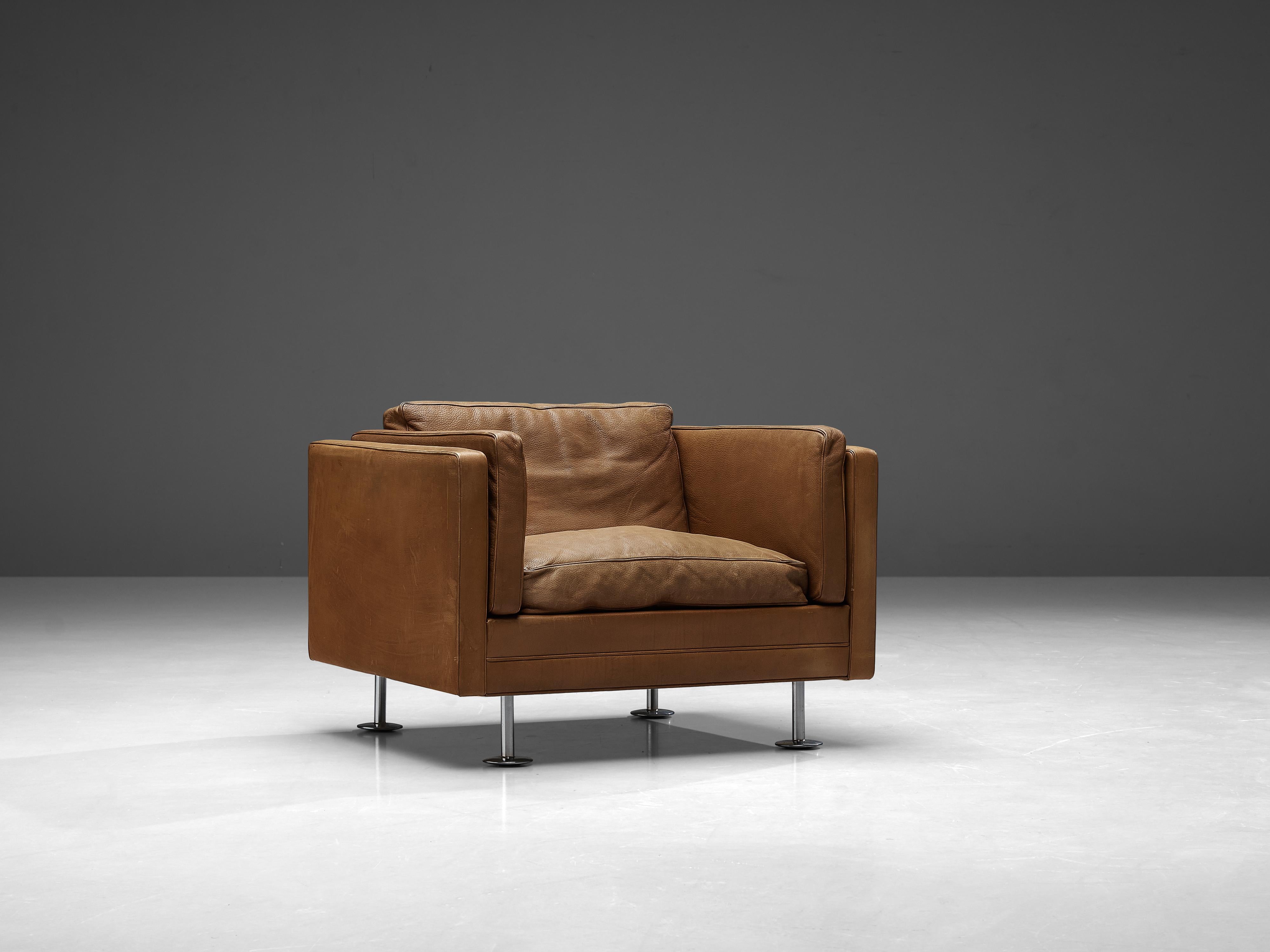 Illum Wikkelsø, lounge chair, leather, stainless steel, Denmark, 1960s. 

Easy chair in cognac leather, by Danish designer Illum Wikkelsø. This club chair has a cubic design. The tight and clean outside is complemented with a soft and comfortable