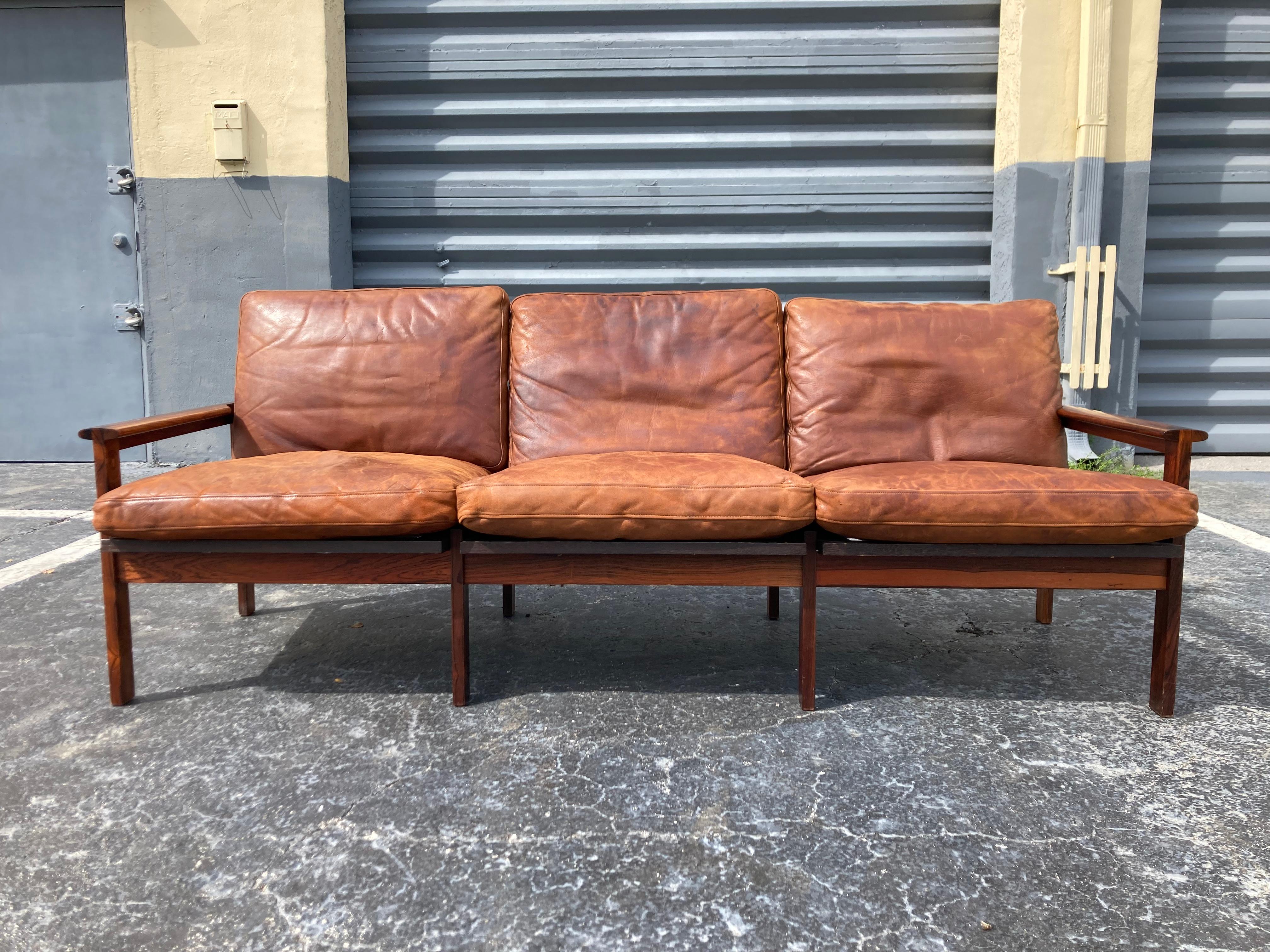 Beautiful Rosewood sofa with cognac leather cushions designed by Illum Wikkelsø.
All original condition.
The Rosewood is beautiful with some normal age-related wear. The leather feels still soft but does have some areas that are dry and starting