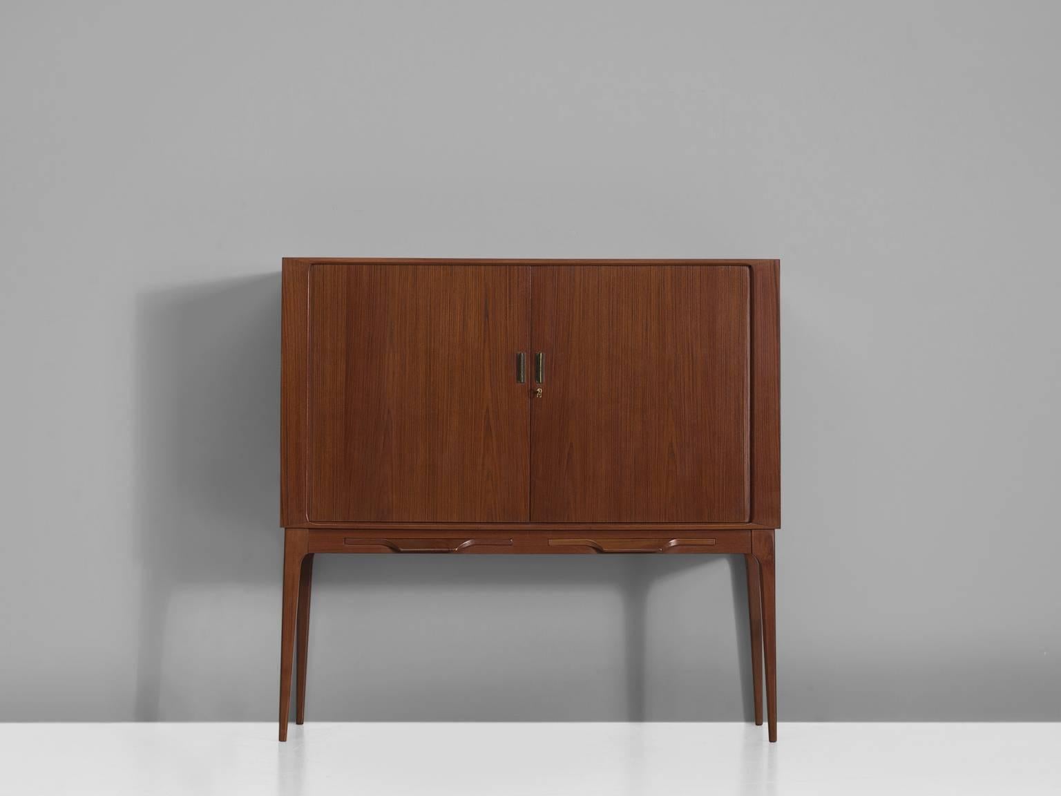 Bar cabinet by Illum Wikkelsø for C.F. Christensen, teak, brass, glass, mirror, Denmark, 1960s.

This elegant high-legged cabinet is designed by Illum Wikkelsø and produced by C. F. Christensen, Silkeborg. The dry bar features cabinet two sliding