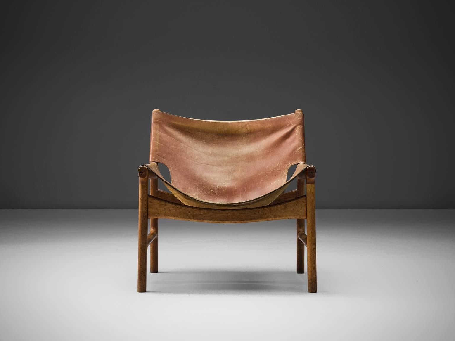 Illum Wikkelsø for Mikael Laursen, easy chair model 103, leather and oak, Denmark, 1960s.

This easy chair is a design by Illum Wikkelsø but produced by master-carver and cabinetmaker Mikael Laursen. The leather is attached to the frame of the chair