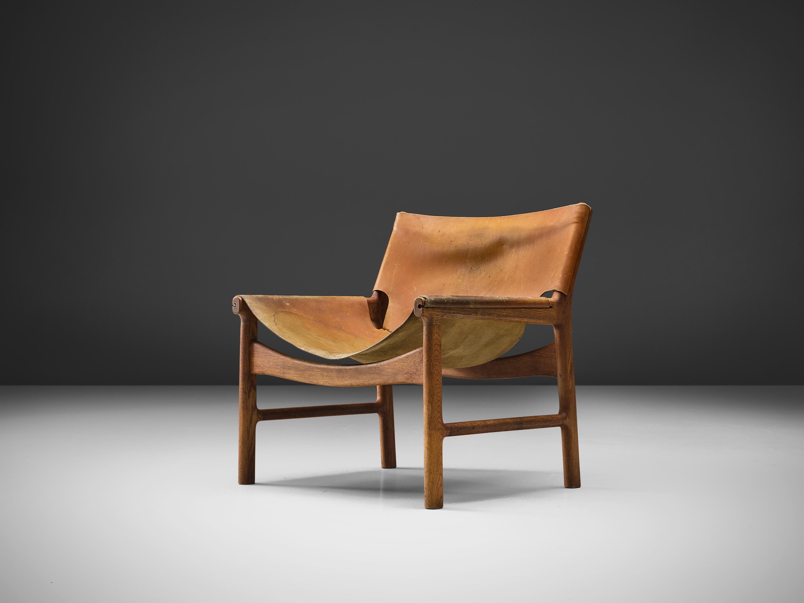 Illum Wikkelsø for Mikael Laursen, easy chair model 103, leather and oak, Denmark, 1960s.

This easy chair is a design by Illum Wikkelsø but produced by master-carver and cabinetmaker Mikael Laursen. The leather is attached to the frame and