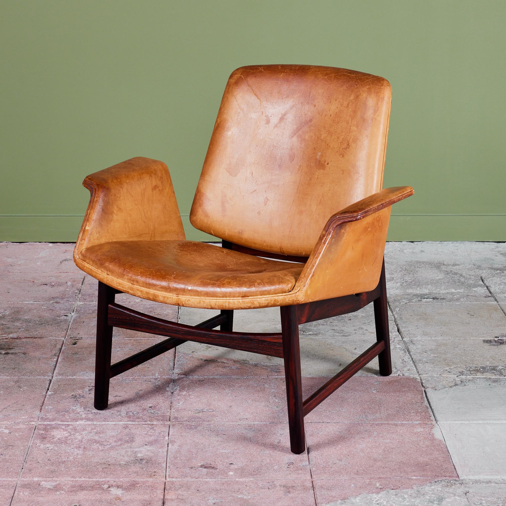 Designed in 1958 by Danish designer Illum Wikkelsø for Aarhus, this lounge chair features the original leather upholstery and stunning rosewood frame. The model 451 lounge chair's frame is wrapped in a beautiful patinated cognac leather with a wide