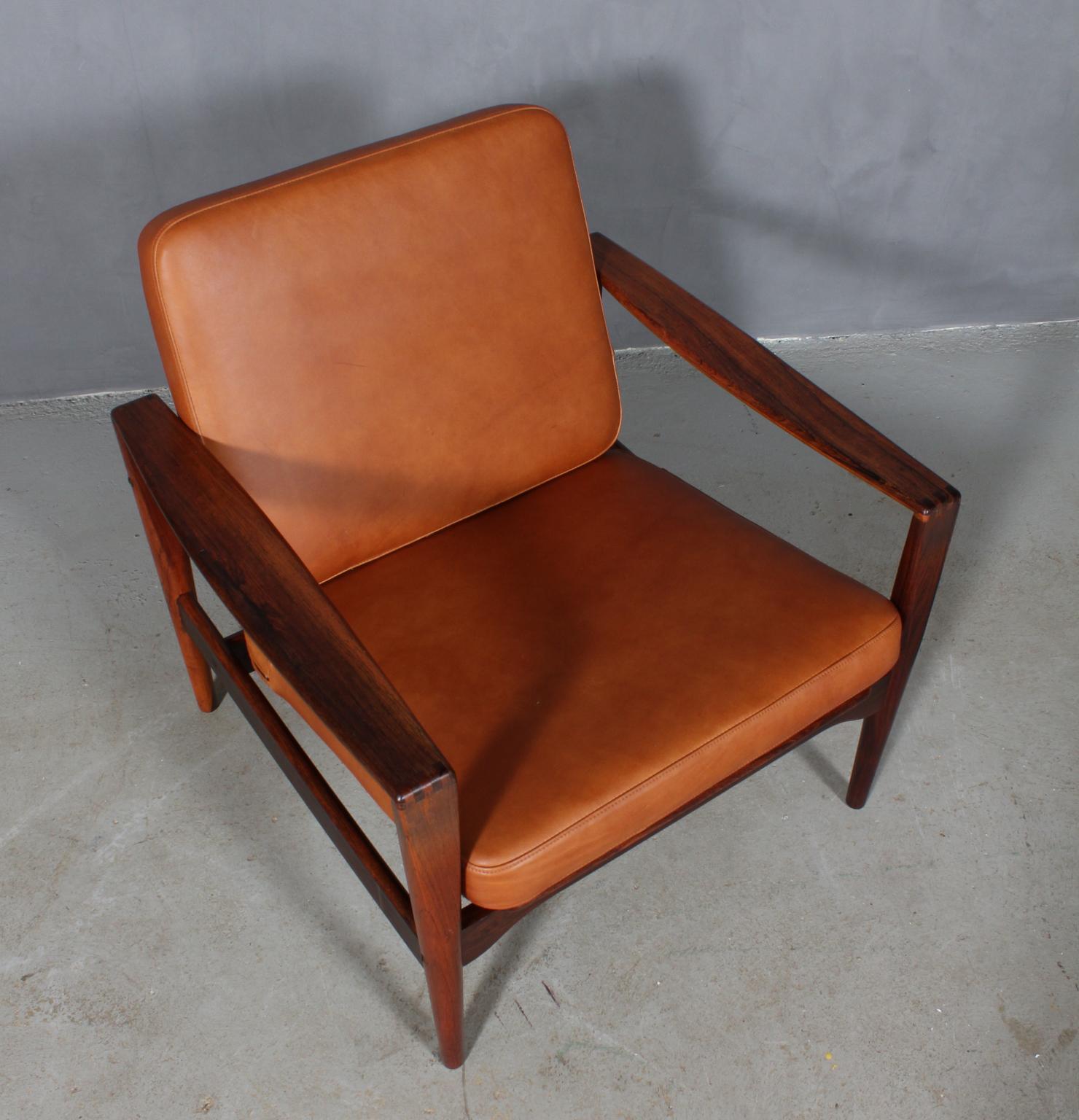 Illum Wikkelsø lounge chair in solid rosewood.

New upholstered cushions in tan Vintage anilin leather.

Model EK. Very rare.