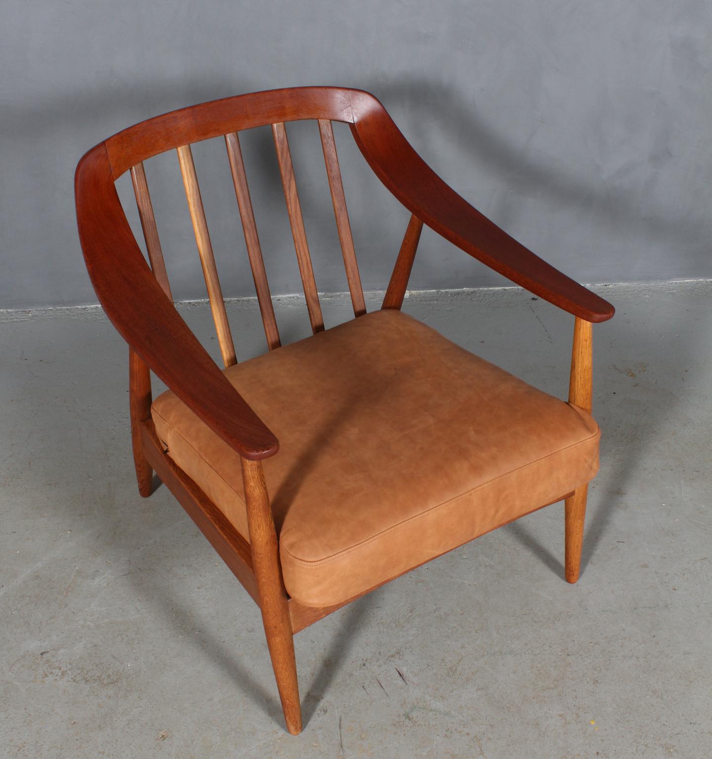 Illum Wikkelsø lounge chair in teak and oak.

New upholstered cushion in tan Dunes anilin leather from Arne Sørensen.

Made by Søren Willadsen.