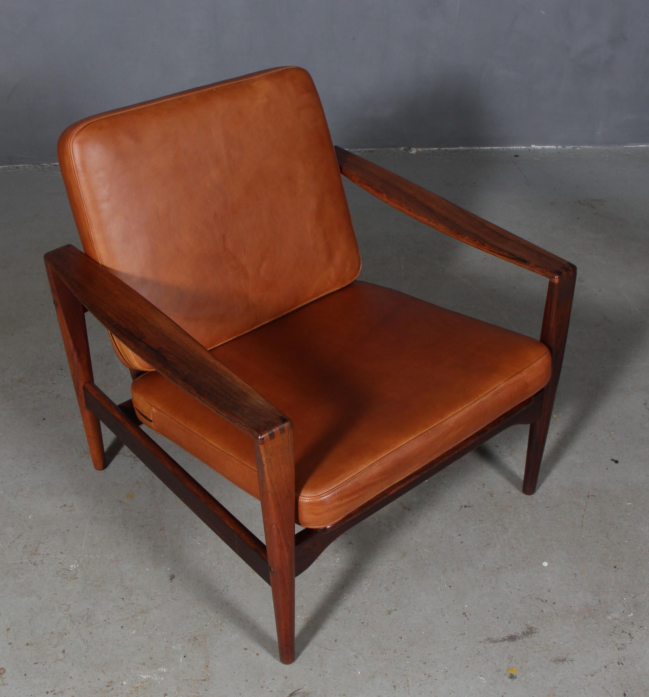 Illum Wikkelsø lounge chair in solid rosewood.

New upholstered cushions in tan Vintage anilin leather.

Model EK. Very rare.