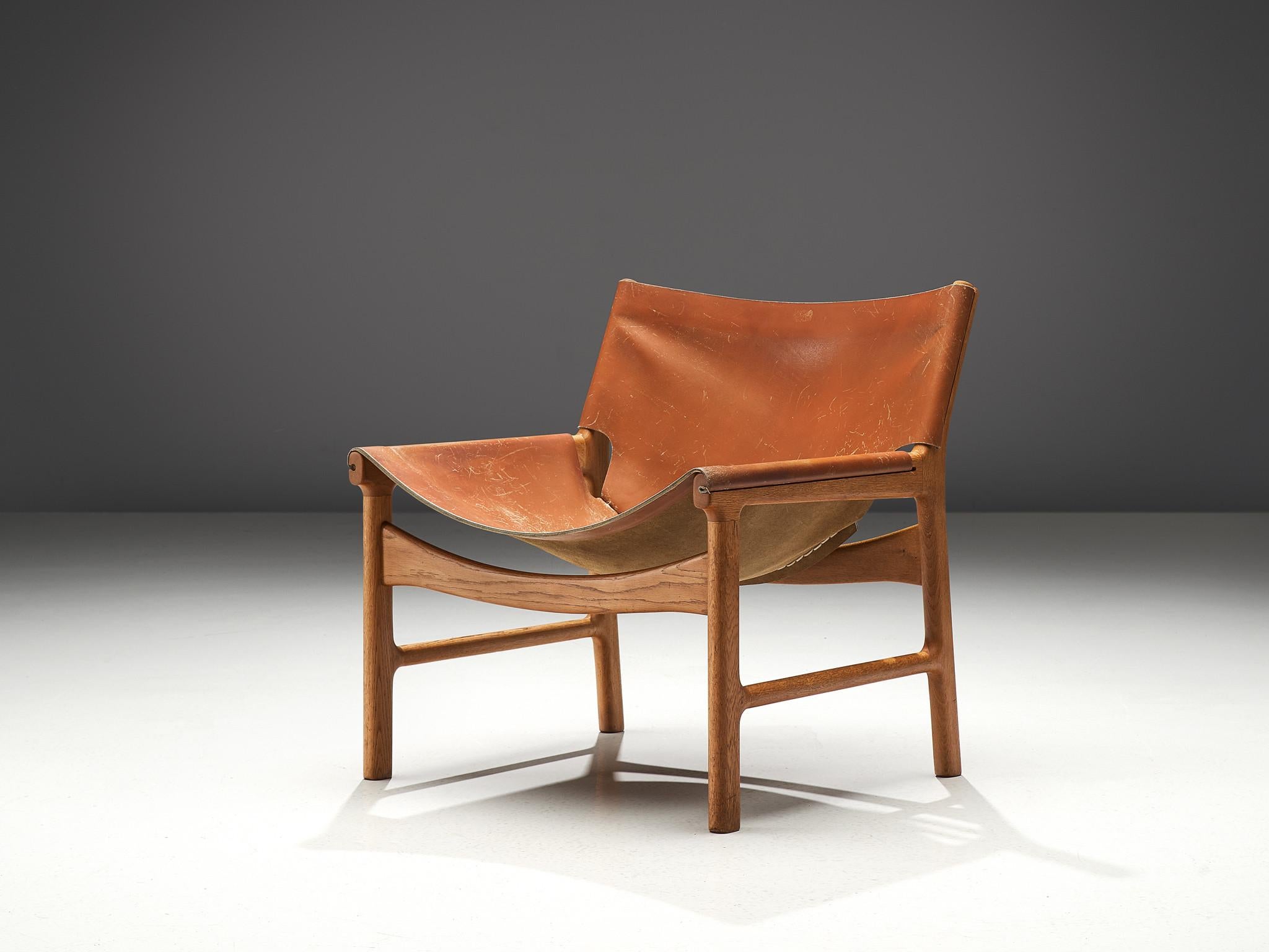 Illum Wikkelsø for Mikael Laursen, easy chair model 103, leather and oak, Denmark, 1960s.

This easy chair is a design by Illum Wikkelsø but produced by master-carver and cabinetmaker Mikael Laursen. The leather is attached to the frame of the