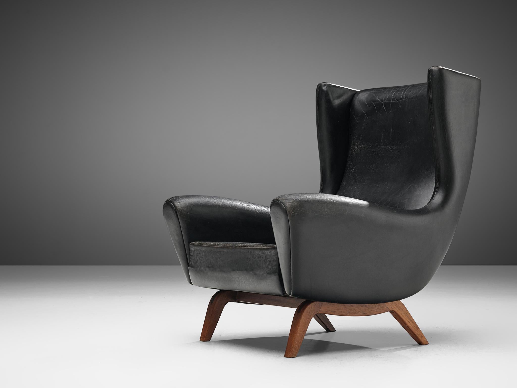 Illum Wikkelsø for Søren Willadsen, wingback chair 'Model 110', teak and black leather, Denmark, 1950s.

This well-designed armchair shows an unusual elegance and great eye for detail, combined with outstanding craftsmanship, which is