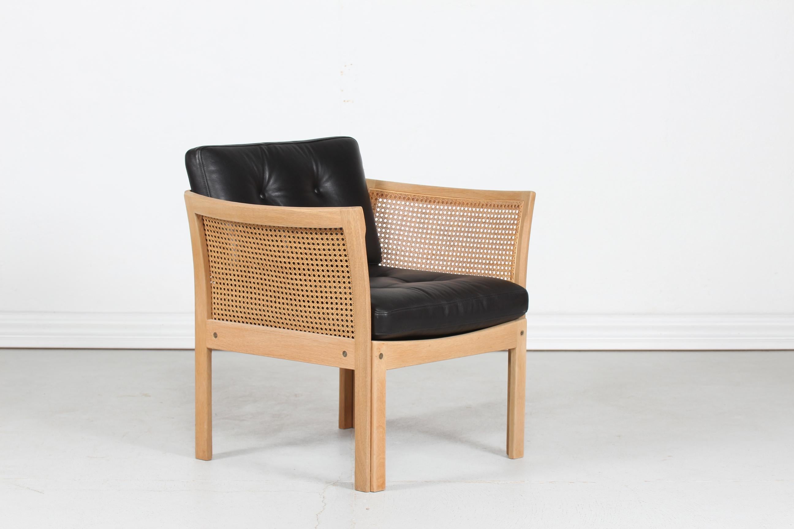 Danish Modern Plexus lounge chair by the Danish furniture designer Kristian Illum Wikkelsø (1919-1999), manufactured by C.F. Christensen, Silkeborg, Denmark.
The chair is made of solid oak. 
The cushions have new upholstery of black leather and