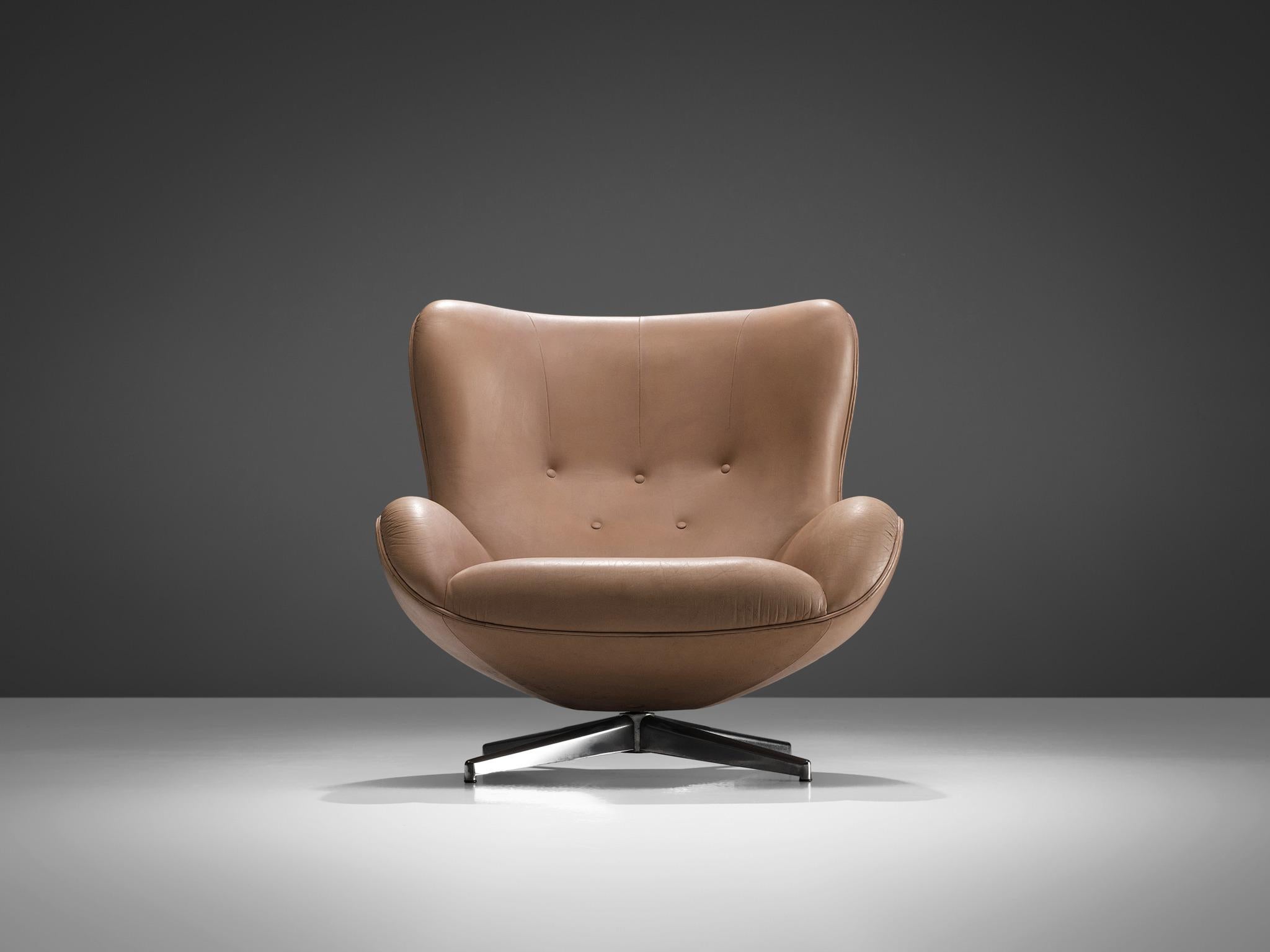 Illum Wikkelsø for A. Mikael Laursen, swivel lounge chair model ML214, cognac leather and metal, Denmark, 1960s.

Organic shaped easy chair in patinated cognac leather by Danish designer Illum Wikkelsø. This swivel chair shows some nice contrasts.