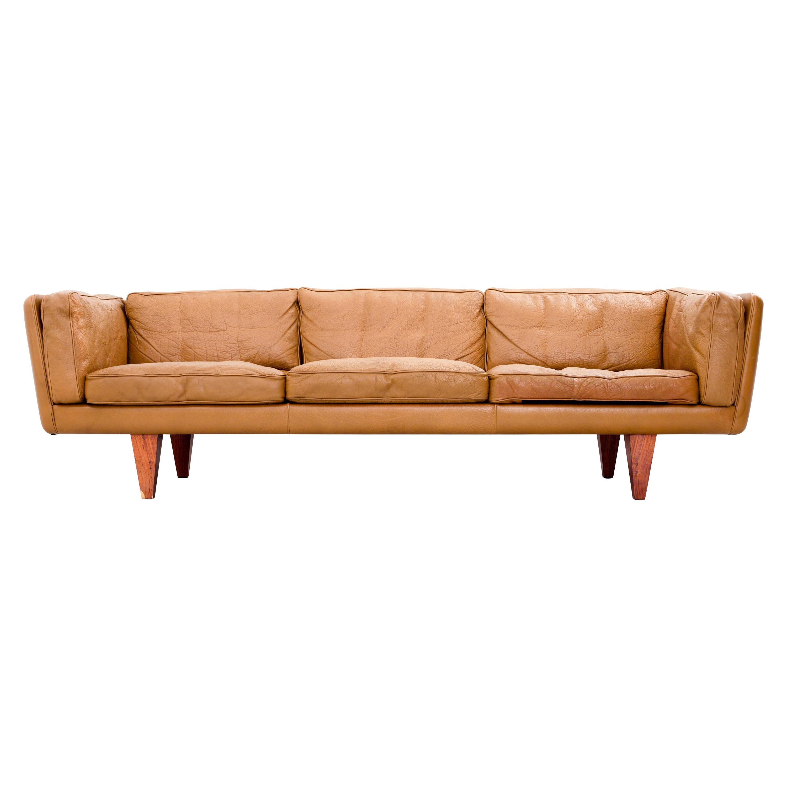 Illum Wikkelsø Three-seat ‘V11’ sofa in cognac coloured leather and wooden pyramid legs. 

Perfect proportions is what makes this V11 sofa by Illum Wikkelsø so special. The  leather runs all the way through, also at the back, making this sofa a