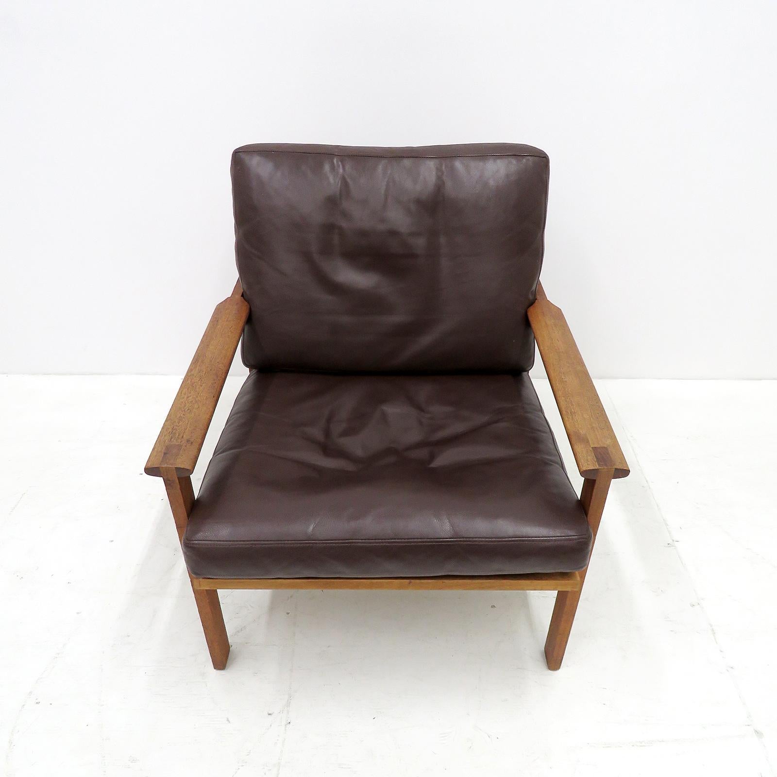 Remarkable pair of easy chairs from the Capella series, designed by Illum Wikkelsø, produced by Niels Eilersen in Denmark, designed in 1959, solid teak wood frames with loose cushions in original dark brown leather with minor normal traces of wear.