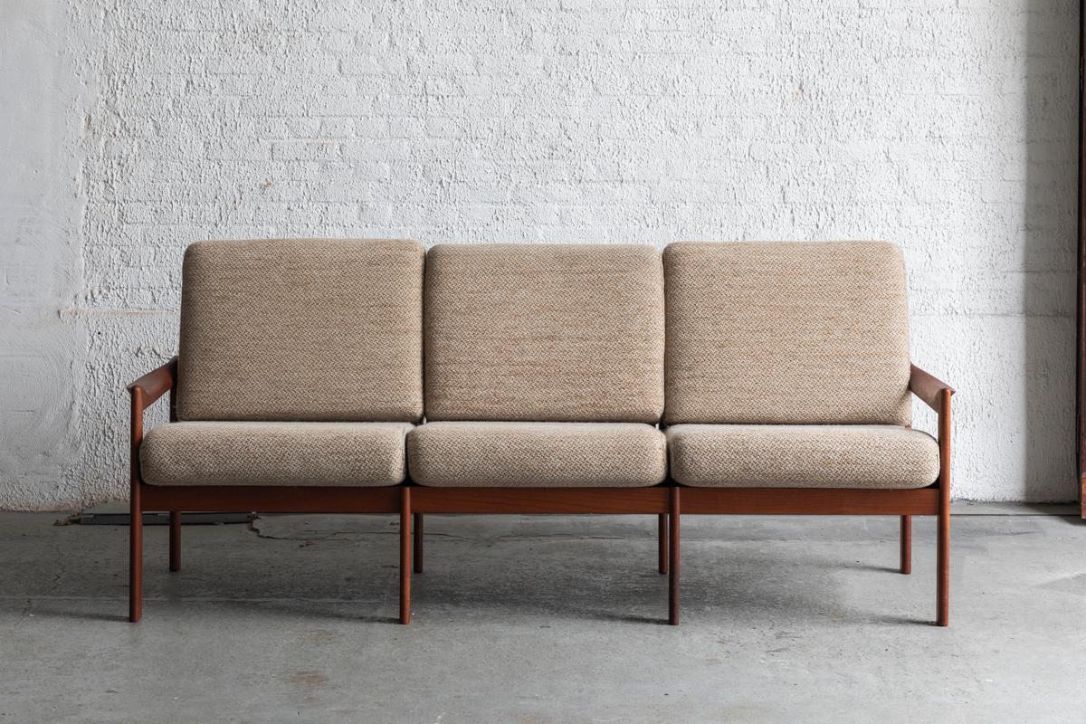 3-seater sofa by Illum Wikkelsø, produced by Eilersen in Denmark in the 1960’s. Solid teak frame garnished with pillows upholstered in the original woolen quality fabric. The singels underneath were renewed to ensure seating comfort. The bench