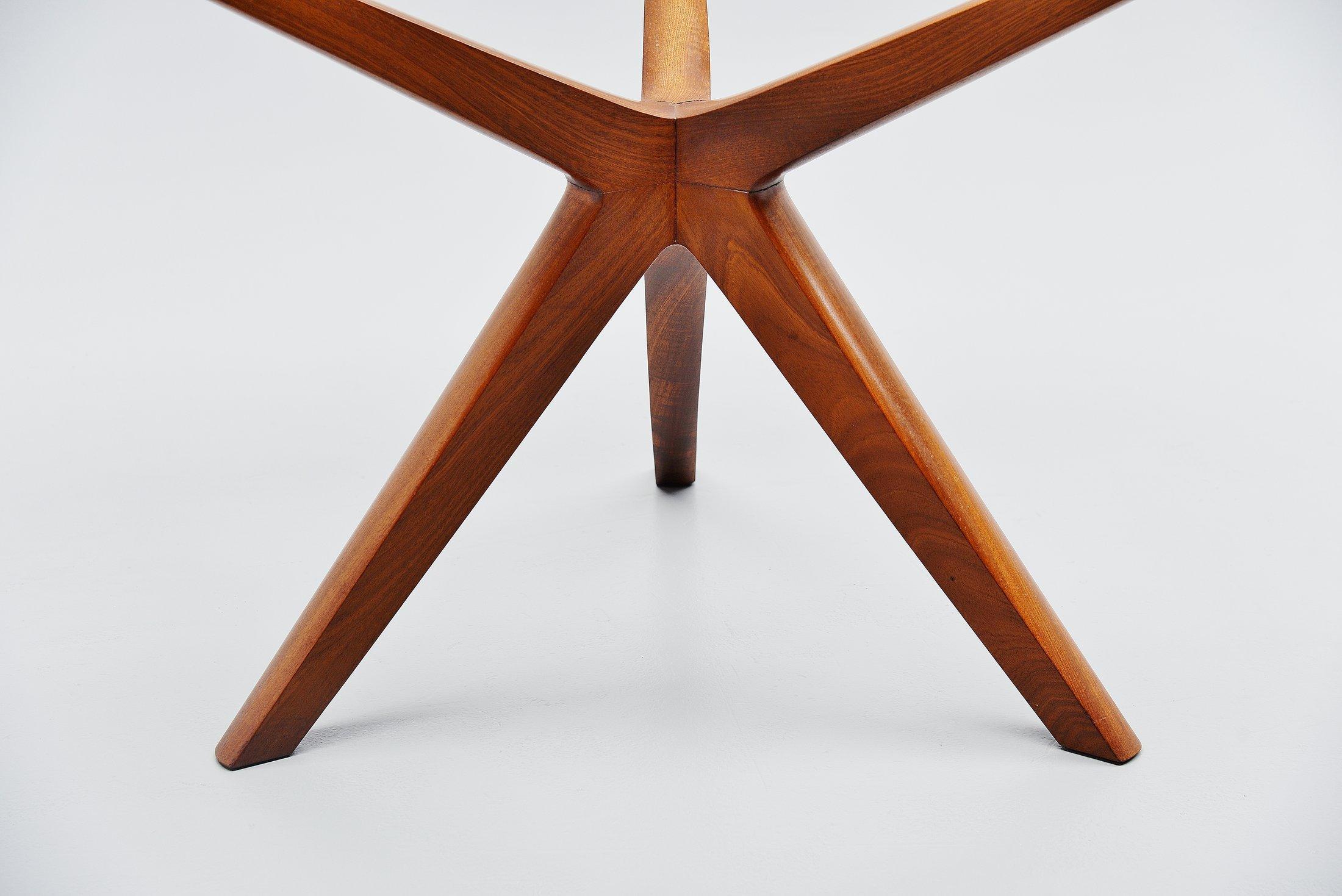 Stunning tripod dining table attributed to a design by Illum Wikkelso, produced in Denmark, 1960. The table is made of solid teak wood and has a glass top. The very nice tripod base looks powerful holding that ring where the glass is fixed. The
