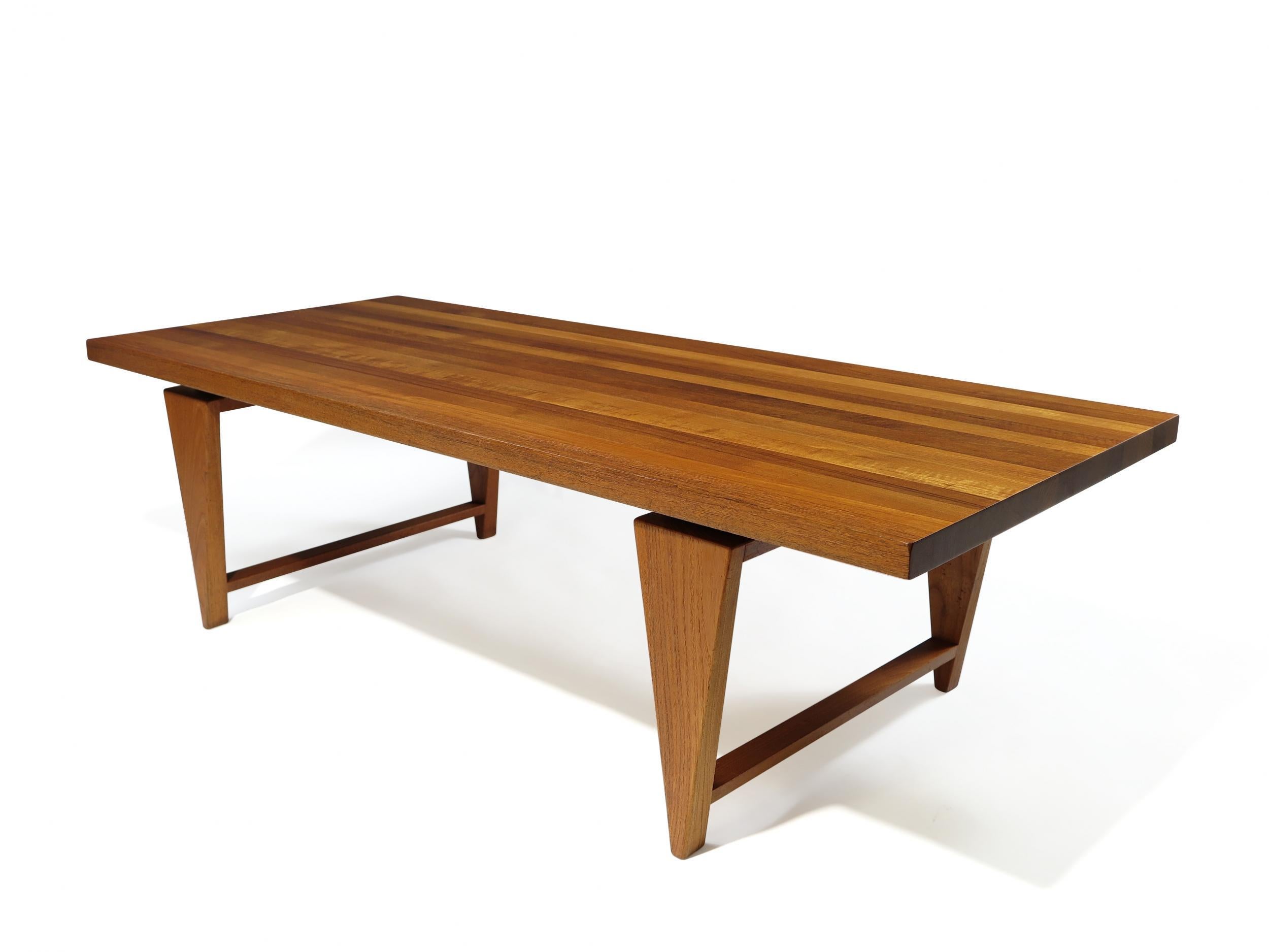 Danish midcentury teak coffee table designed by Illum Wikkelso for Mikael Laursen, Model ML 115 Denmark. Crafted of the solid teak plank, raised on sculptural angled legs.