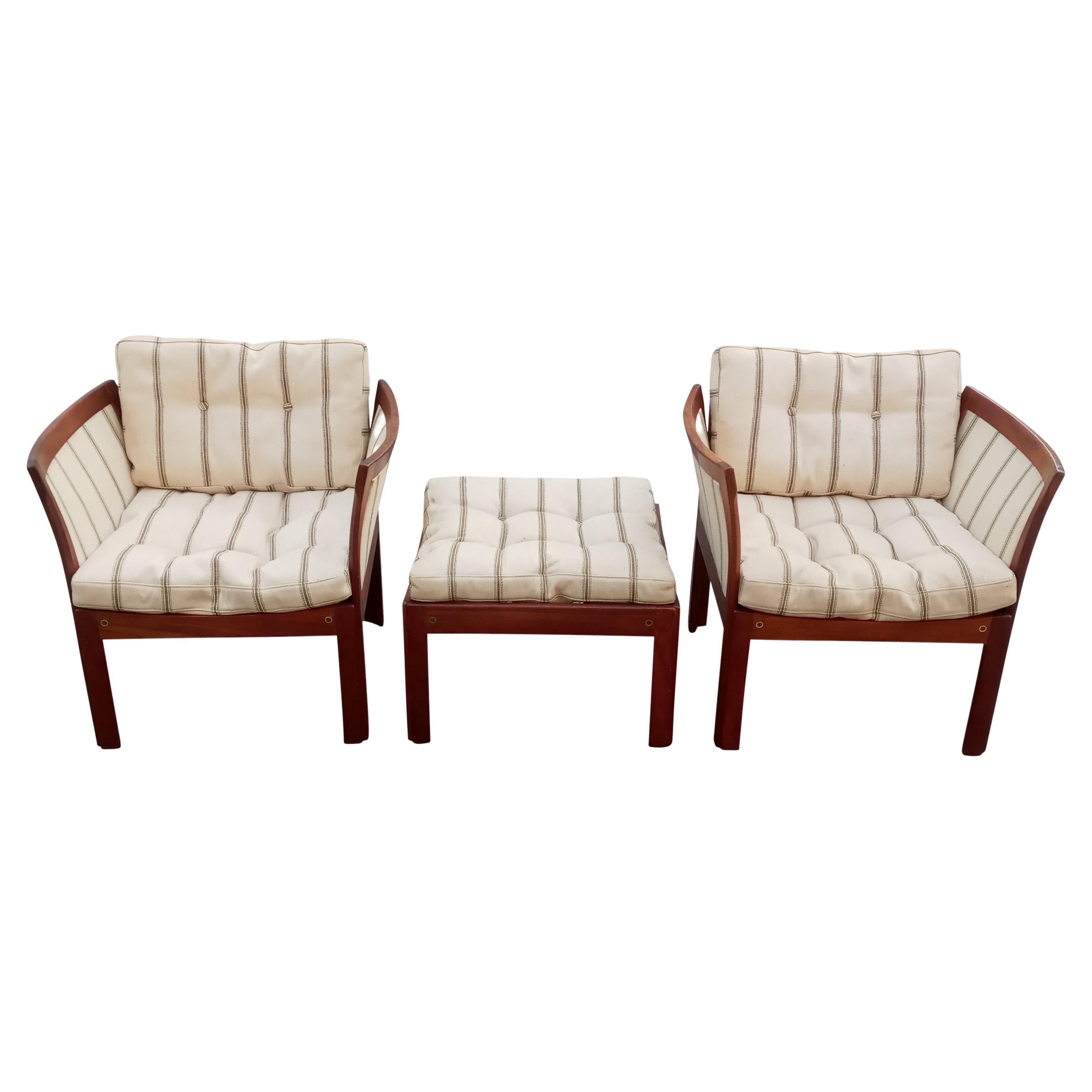 This vintage Danish set is constructed of teak and retains the original striped wool upholstery. The visual lightness of this Nordic styling is complemented by an unparalleled comfort. The finish on the frames shows a warm, natural patina. There is