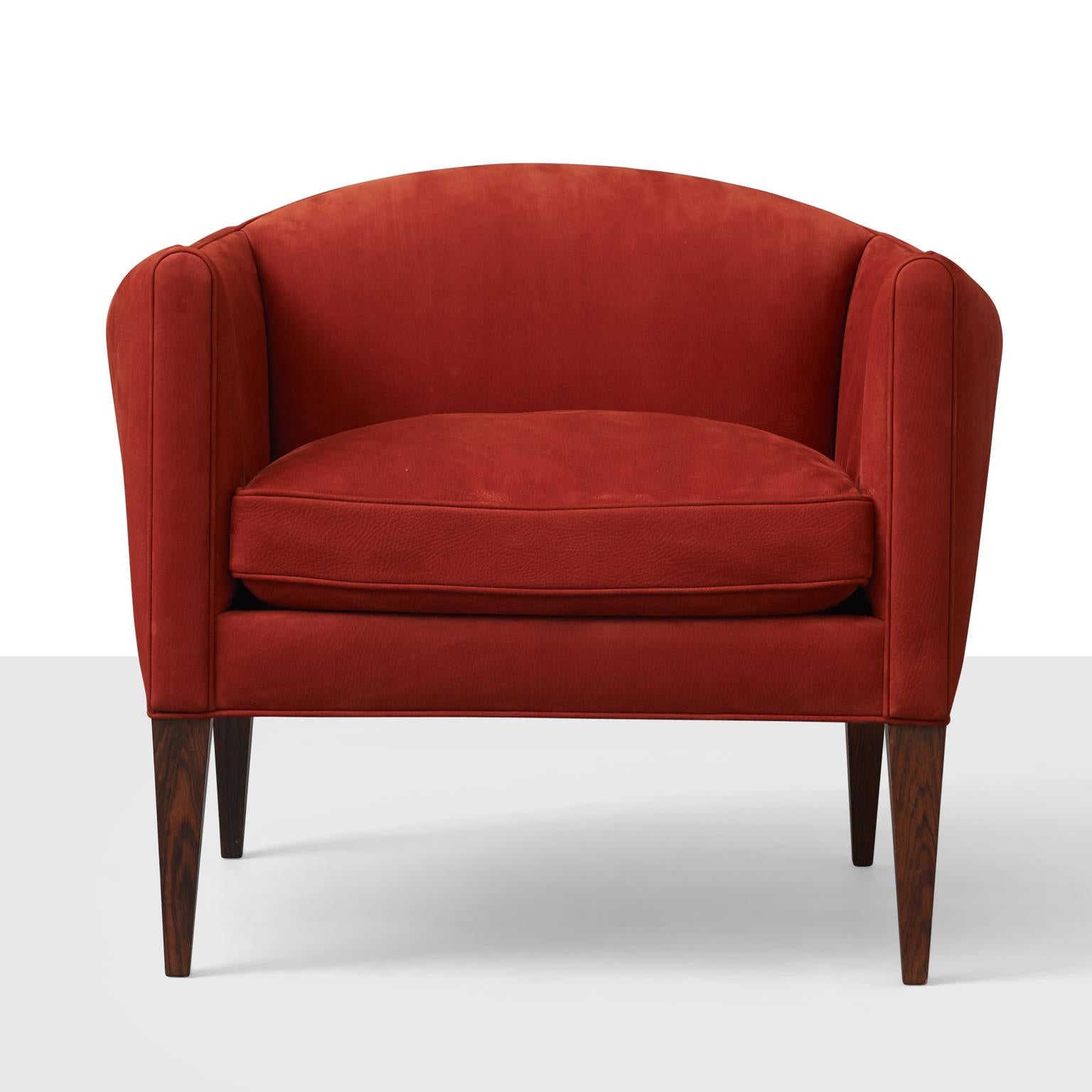 Un fauteuil Illum Wikkelsø, précédemment retapissé en cuir nubuk rouge, sur des pieds fuselés en bois de rose. 