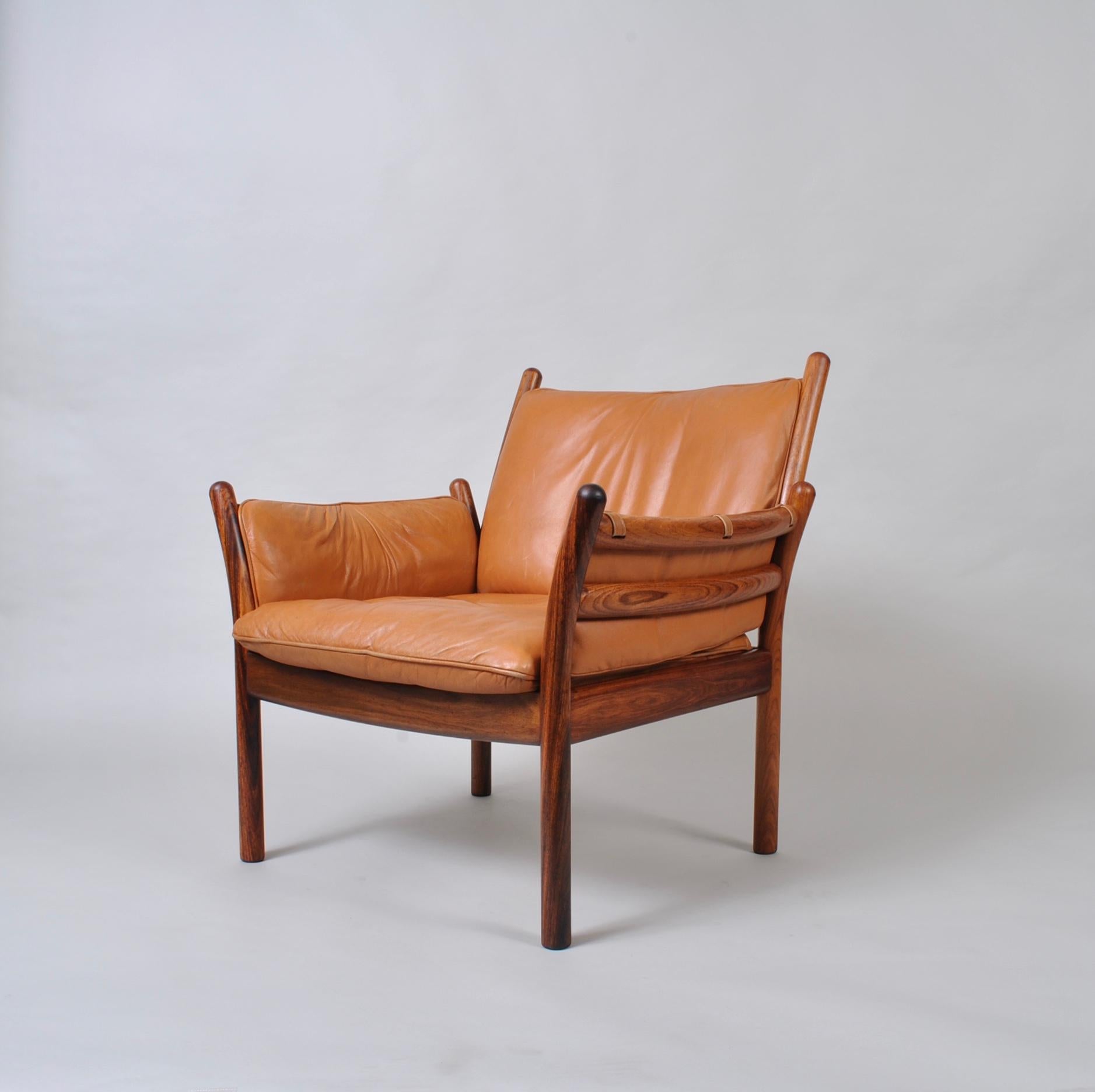 The wonderfully sculptural ‘Genius’ Lounge chair designed by Illum Wikkelso. Solid rosewood frame with original tan leather upholstery. Incredible craftsmanship. Reupholstery is available at an extra cost. Enquire for further details. Produced by