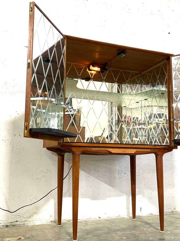 Illum Wikkelsø Mueble cóctel o mueble bar de teca, diseñado para C.F. Christensen. Fabricado en Dinamarca. Interior con espejos Harlekin. Un estante de cristal en el interior. 31,75″ de ancho x 16″ de fondo x 45″ de alto