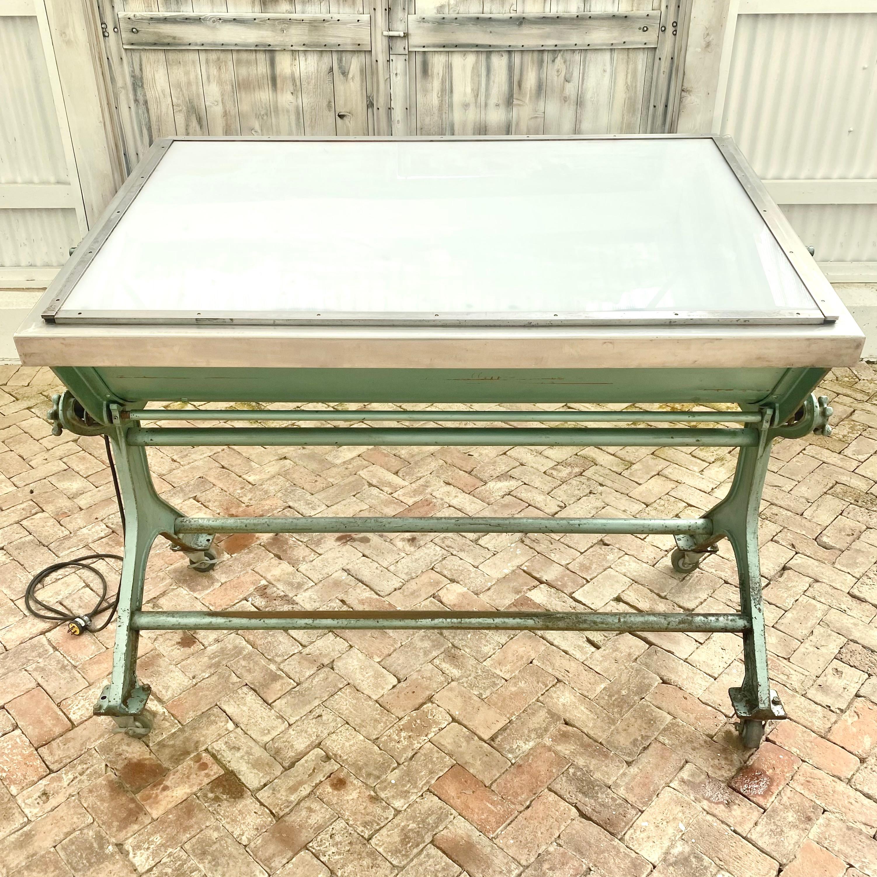 Incredible industrial grade light box drafting table. Extremely heavy and well made in the US, circa 1950s. Glass tabletop allows the light of two enclosed fluorescent tube lights to illuminate the surface. Knobs on either side of the table can be